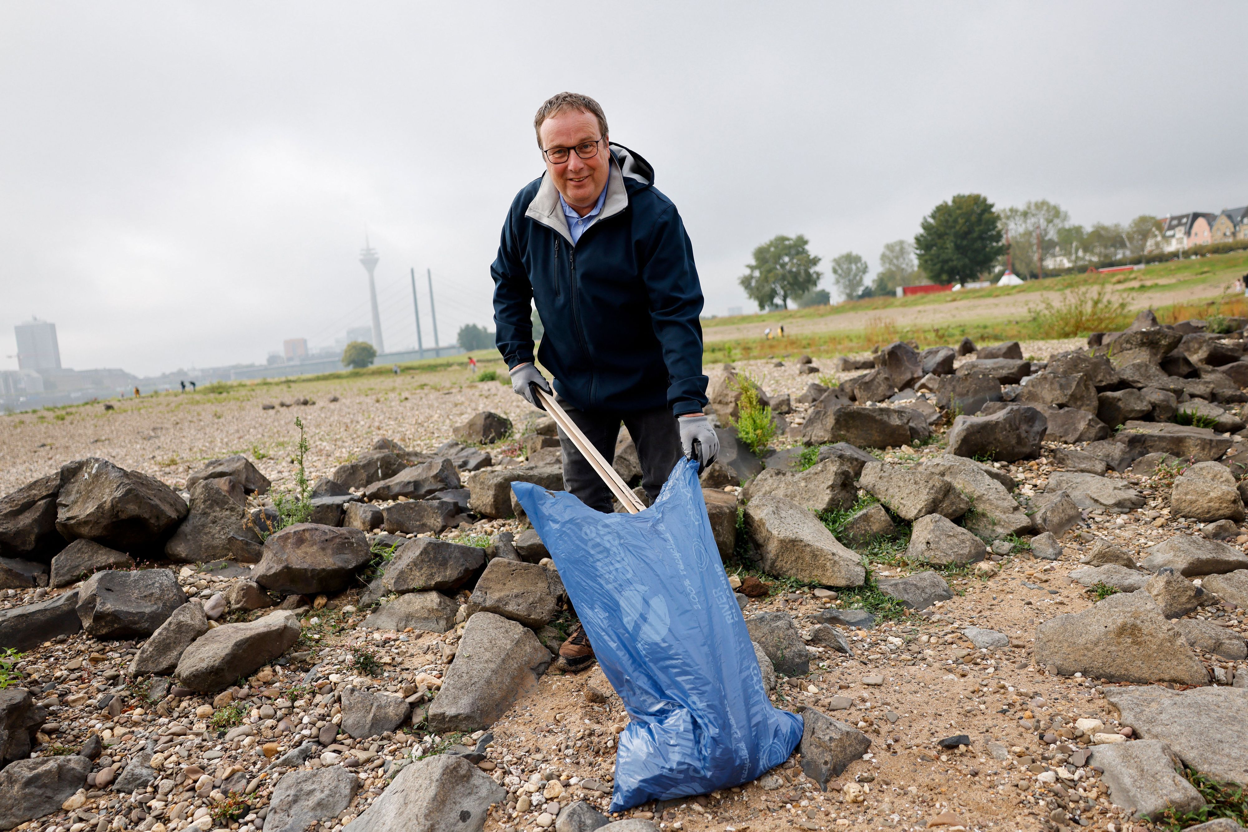 Oliver Krischer (Bündnis 90/Die Grünen), Minister für Umwelt, Naturschutz und Verkehr des Landes Nordrhein-Westfalen, sammelt auf den Düsseldorfer Rheinwiesen Müll auf.