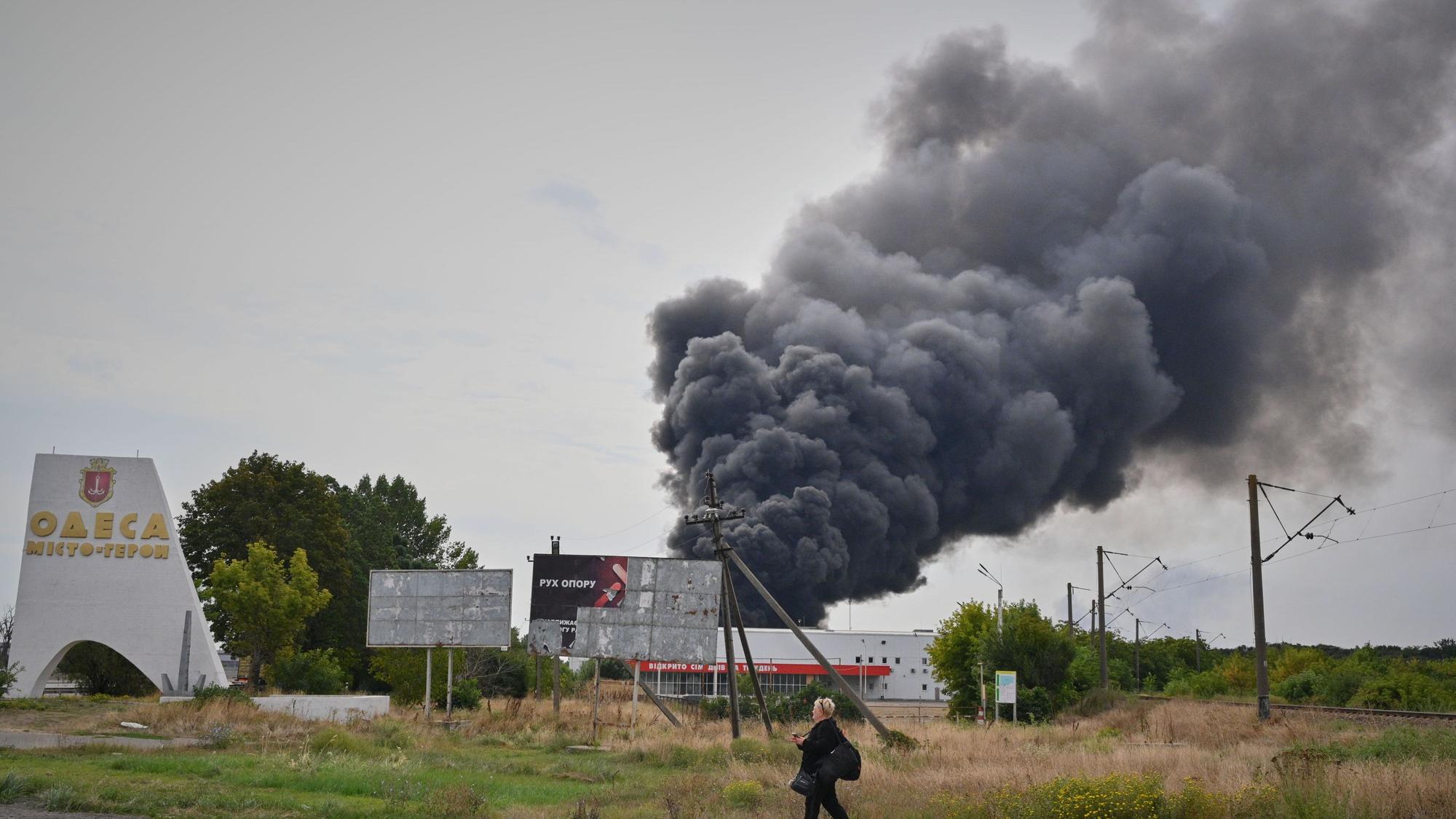 Eine Frau geht nach einem russischen Luftangriff an einem brennenden Lagerhaus am Stadtrand vorbei.