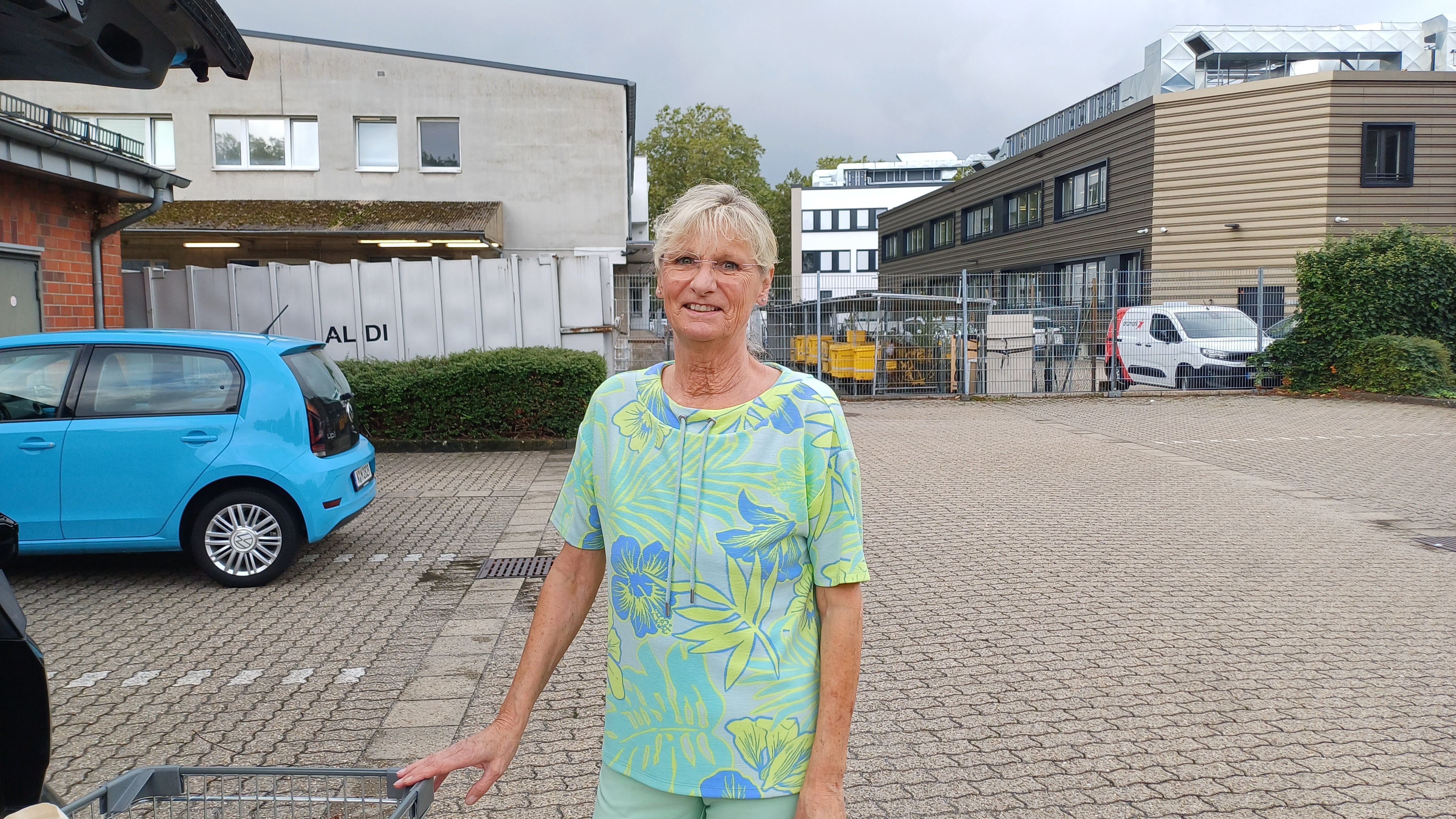 Eine Frau steht vor ihrem Auto auf dem Parkplatz