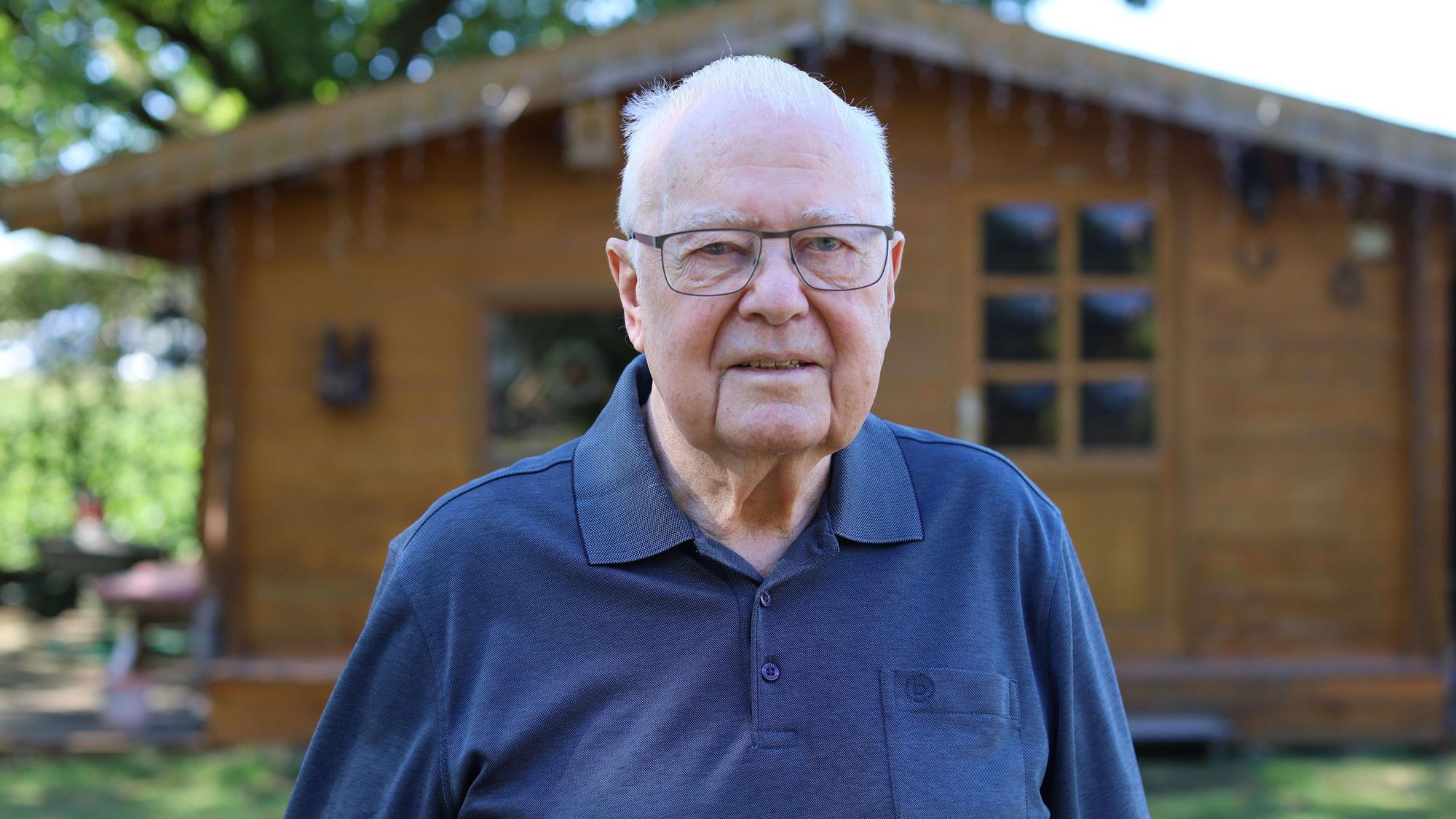 Roland Kierspel ist 88 Jahre alt. Er ist im Garten vor einem Schrebergartenhaus aus Holz zu sehen.