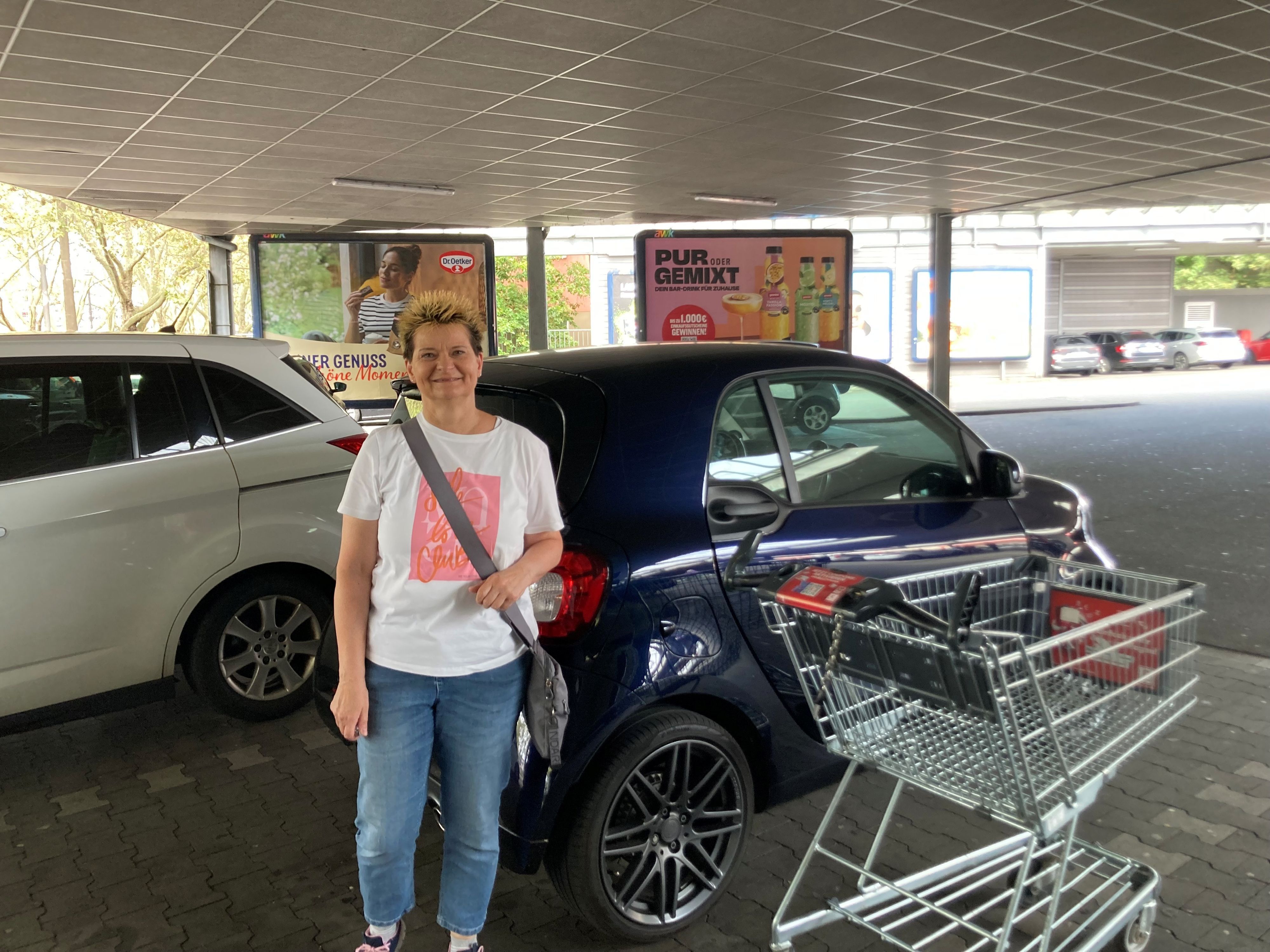 Eine Frau steht vor ihrem Auto.