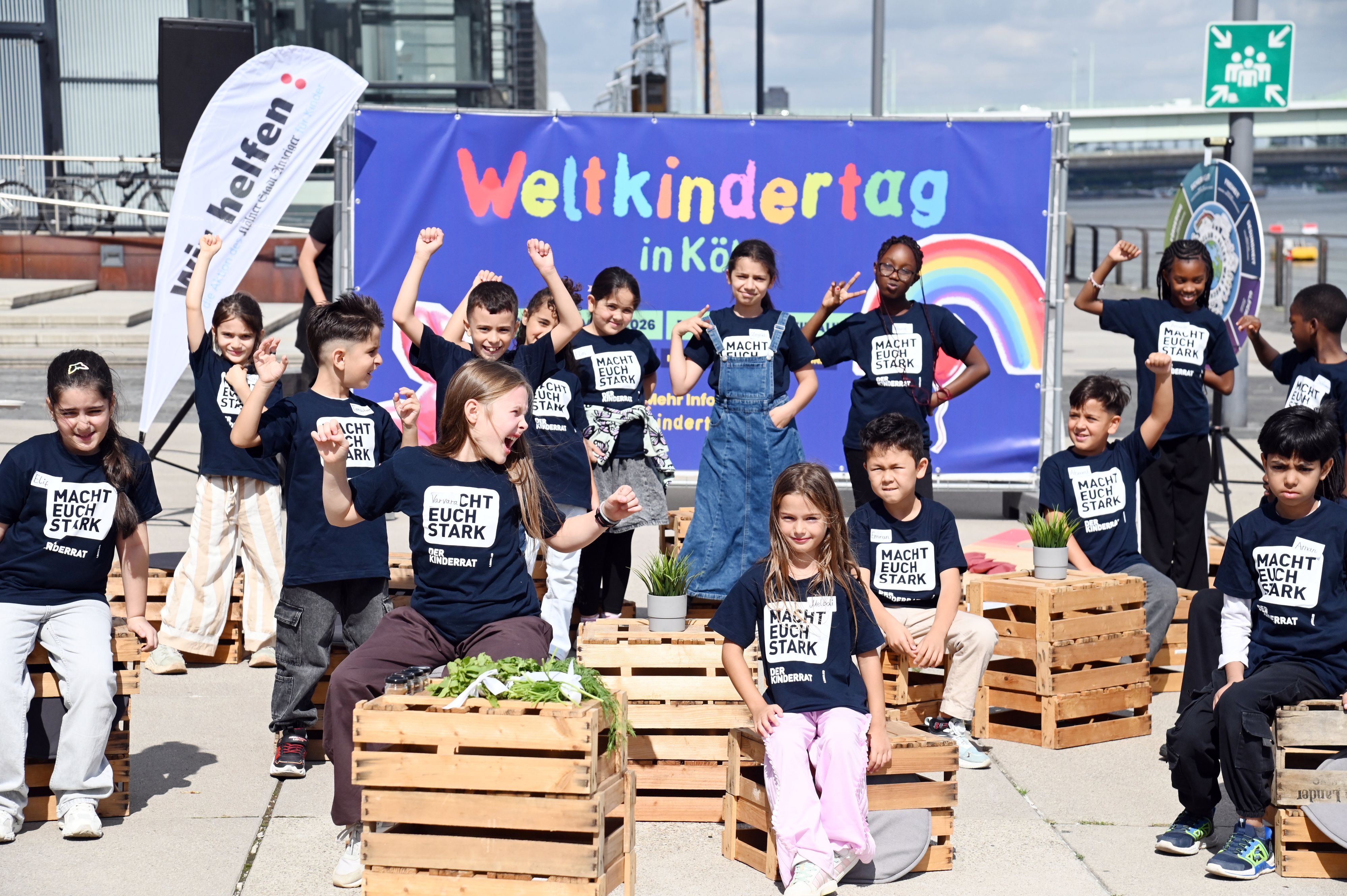 Die jungen Mädchen und Jungen des Kinderrats vom Linoclub stehen am Harry-Blum-Platz im Rheinauhafen vor einem Plakat zum Weltkindertag am 20.September in Köln