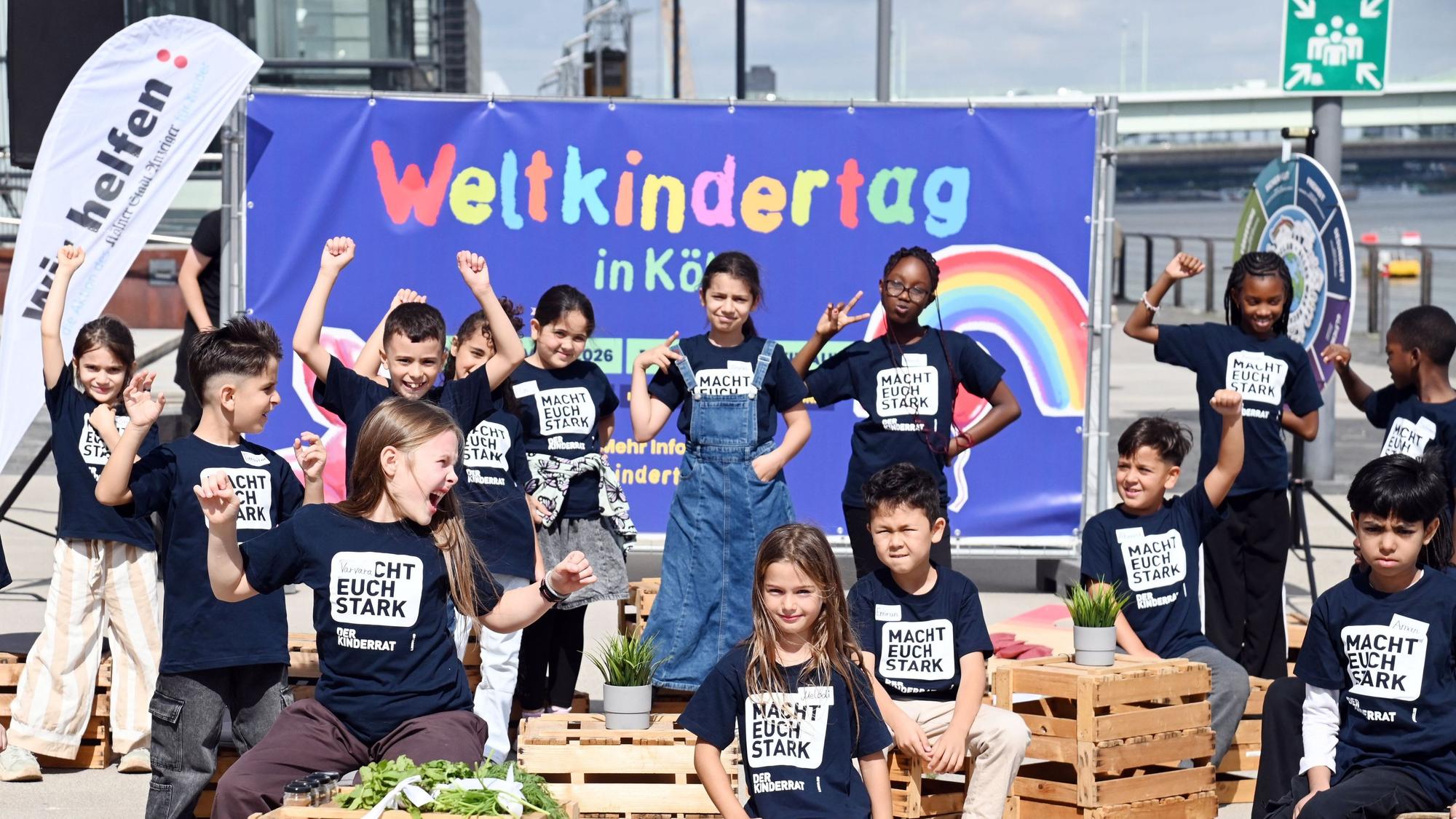 Die jungen Mädchen und Jungen des Kinderrats vom Linoclub stehen am Harry-Blum-Platz im Rheinauhafen vor einem Plakat zum Weltkindertag am 20.September in Köln