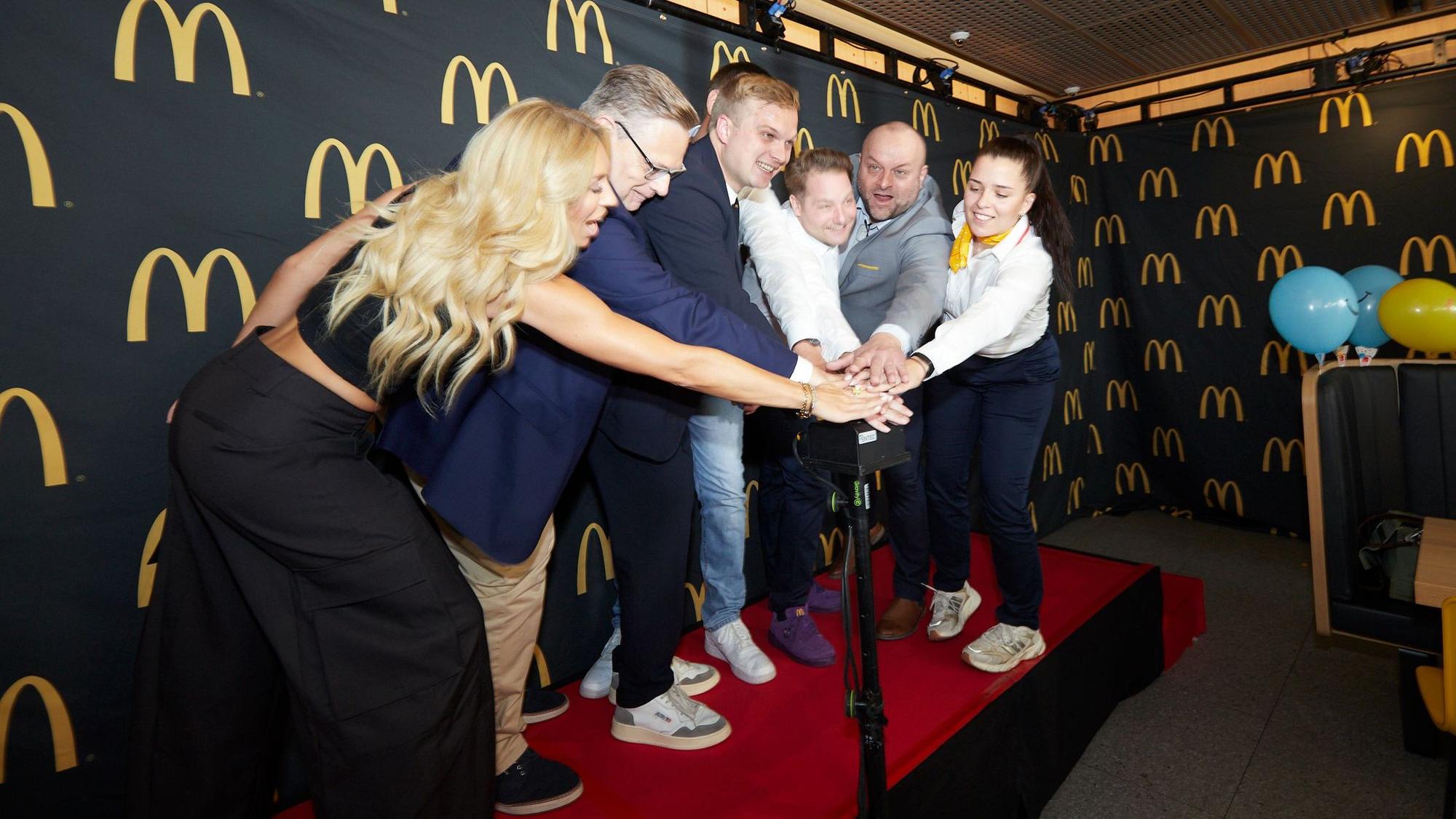 Betreiber Mats Riepenhausen und Gäste drücken zur Eröffnung der neuen McDonalds'-Fliliale gemeinsam auf einen Buzzer.