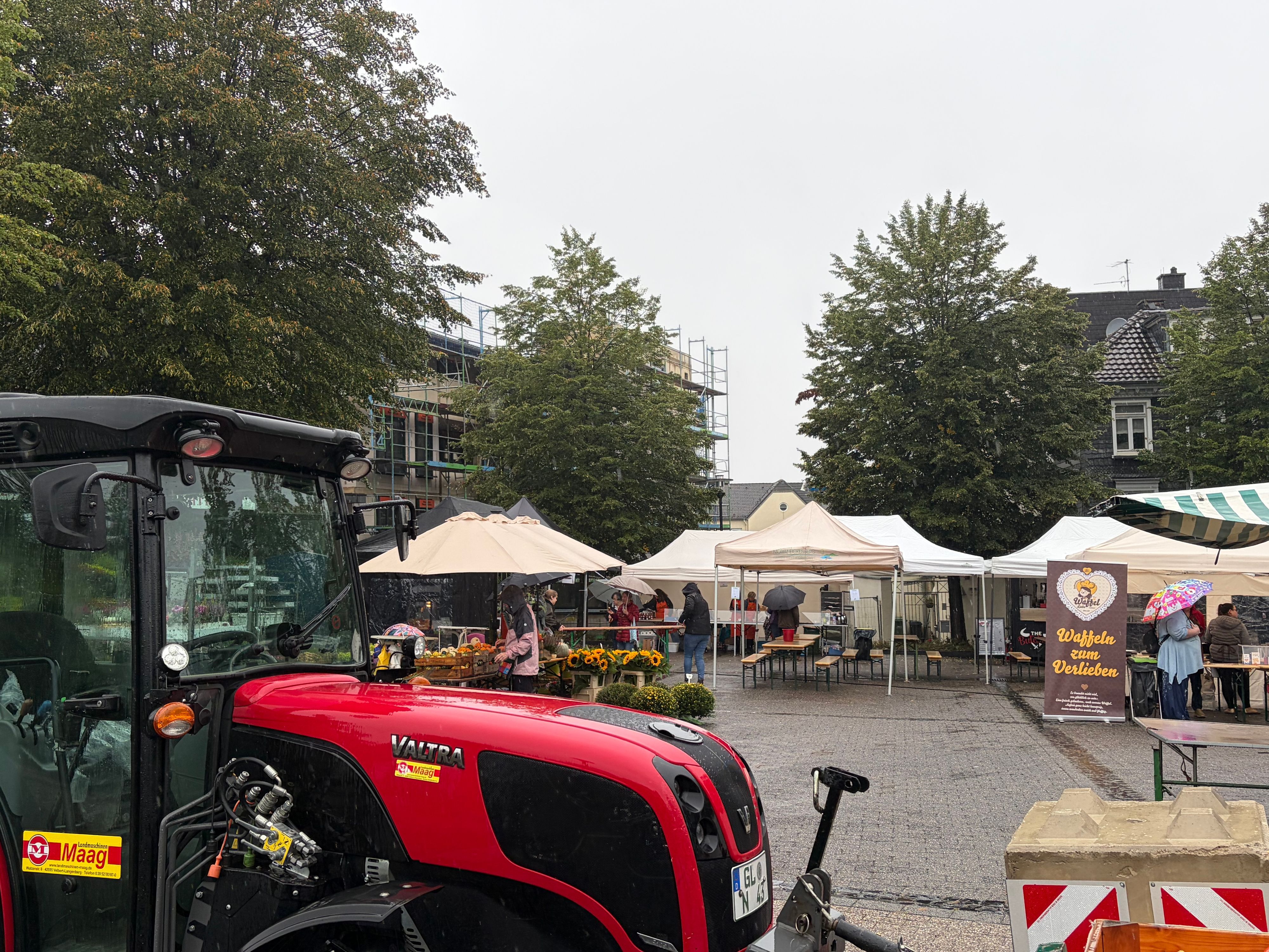 Ein Traktor steht auf einem Platz mit Markständen.
