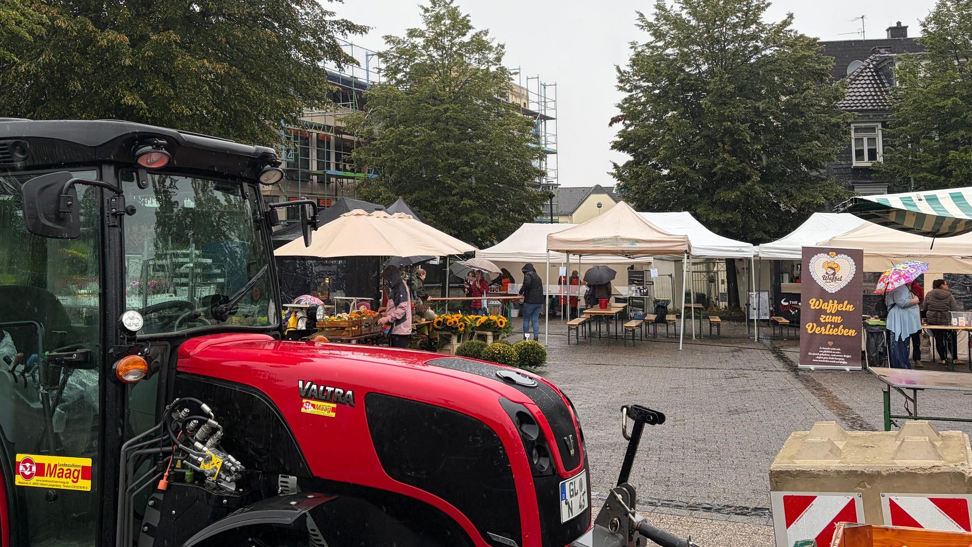Ein Traktor steht auf einem Platz mit Markständen.