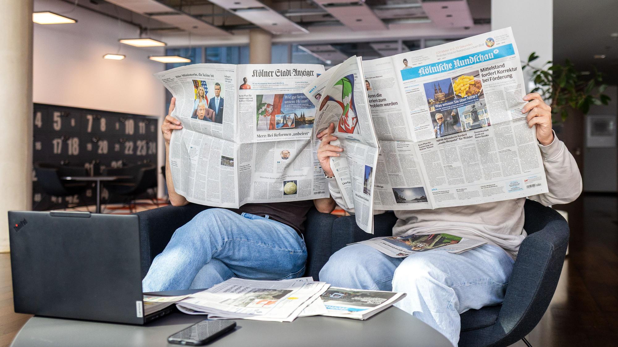 Zwei Menschen lesen Zeitung