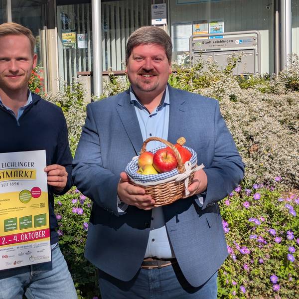 Zwei Männer halten ein Plakat und einen Obstkorb.