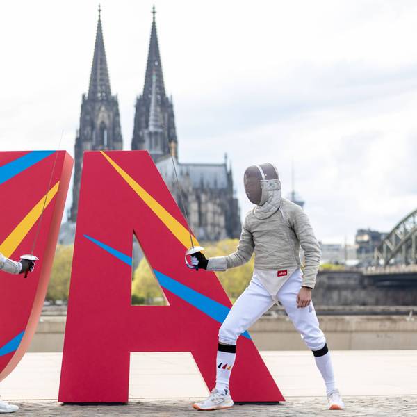 Zwei Fechter vor eine JA Logo vor dem Kölner Dom.