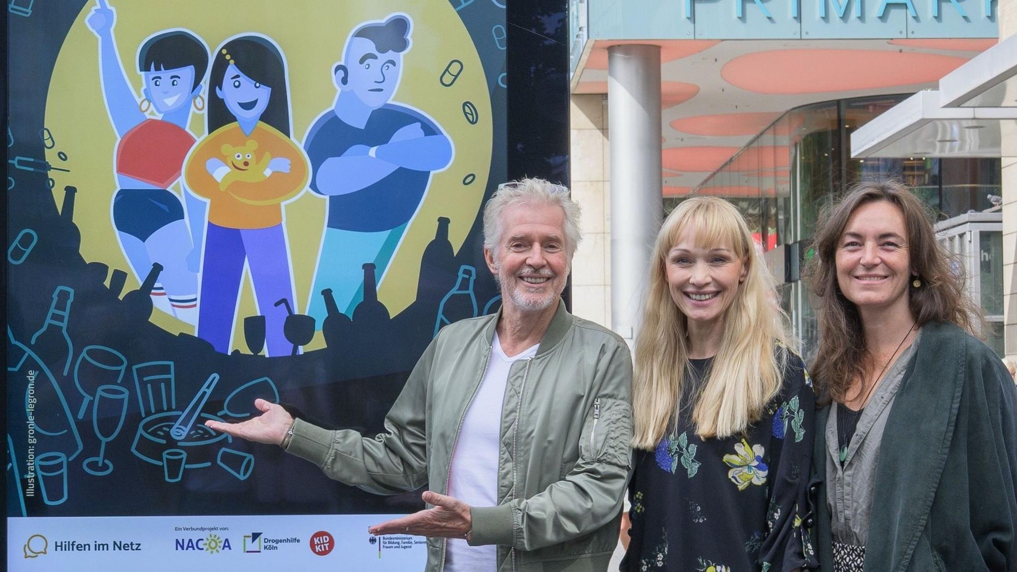 Bestsellerautor Frank Schätzing, Anna Buning (Leiterin der Onlineberatung Kidkit) und Tanja Ruppert, Sozialarbeiterin bei NACOA Deutschland e.V., präsentieren die neue Plakataktion am Kölner Neumarkt.