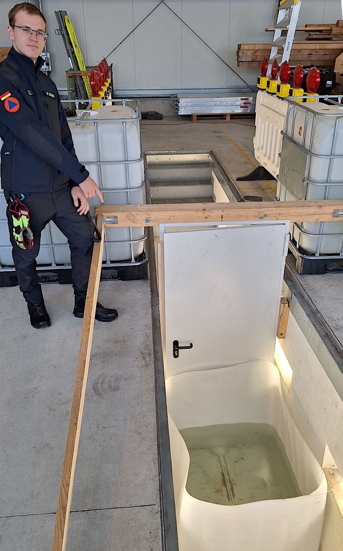 Das Bild eine Tür, vor der eine Wanne mit Wasser steht.