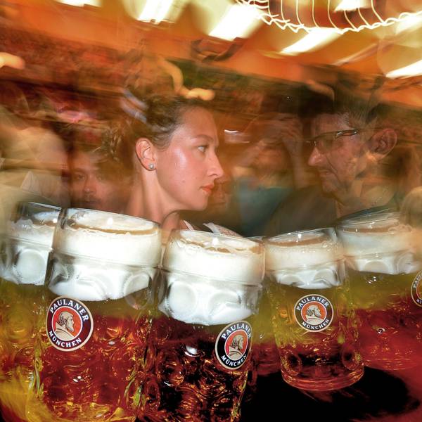 Eine Bedienung trägt im Paulaner-Festzelt Maßkrüge mit Bier (Unschärfe durch lange Belichtungszeit).