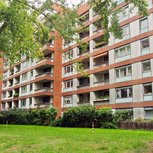 Mehrstöckige Wohnblocks stehen hinter einer Rasenfläche.