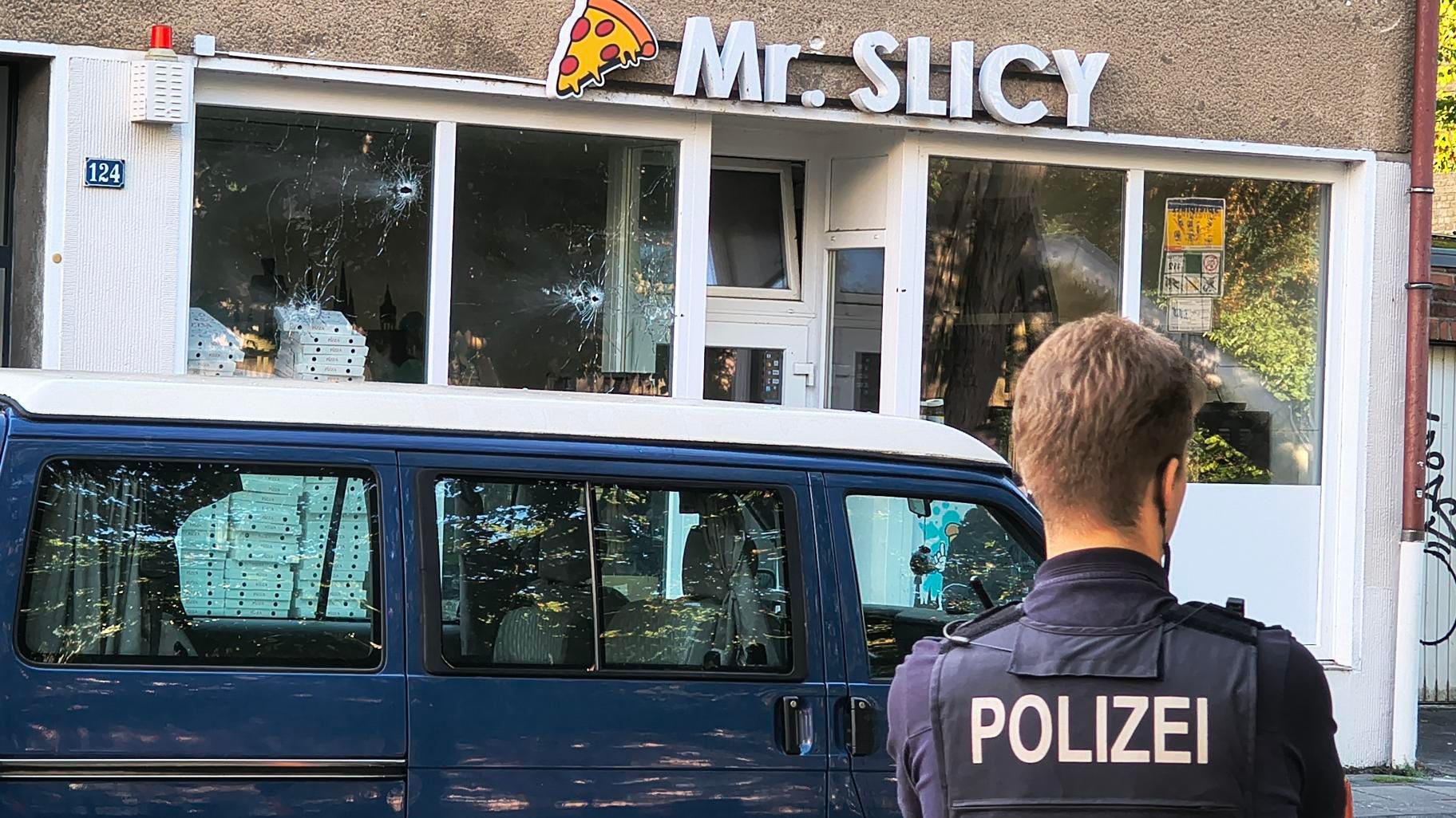 Einschusslöcher sind in den Scheiben einer Pizzeria zu sehen.