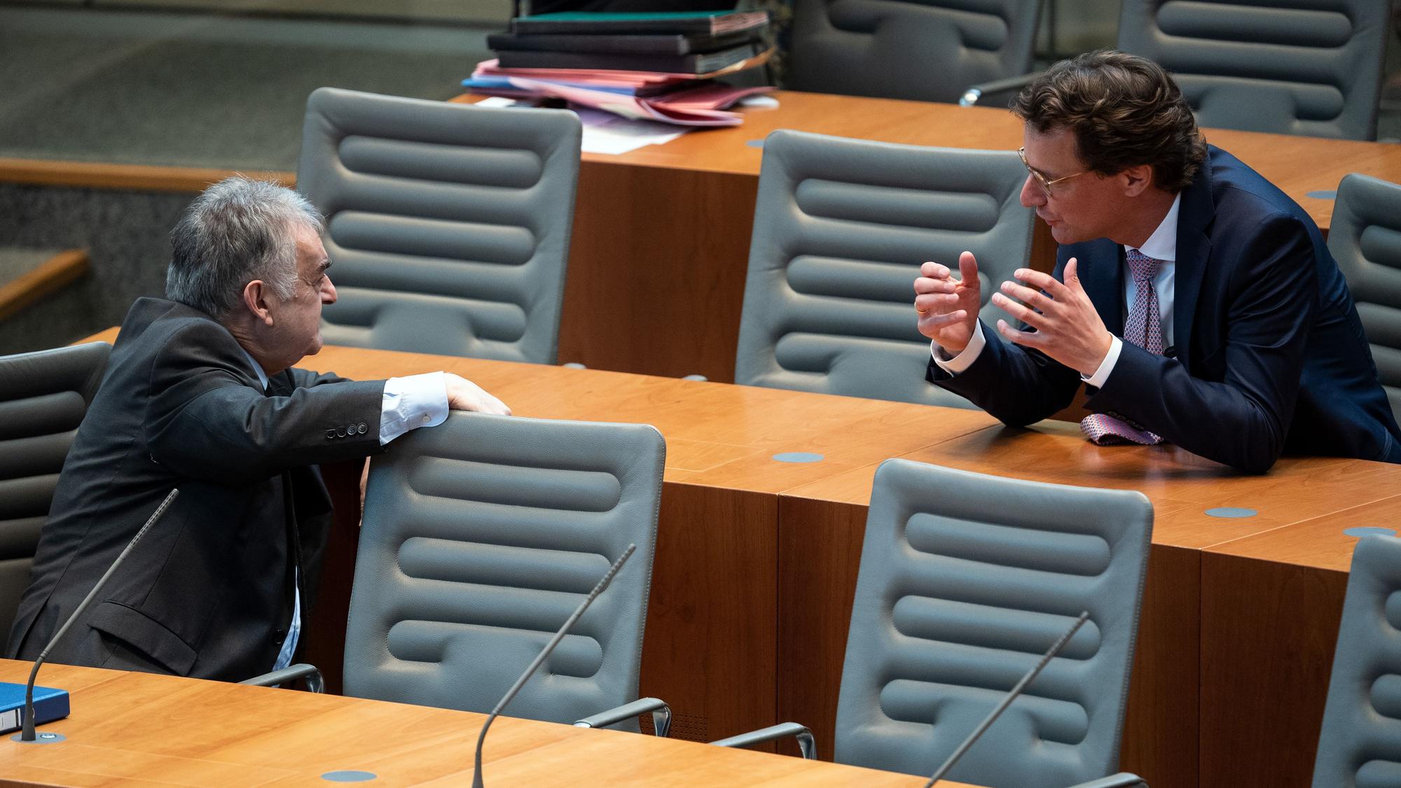 Herbert Reul (l), Innenminister von Nordrhein-Westfalen, und Hendrik Wüst unterhalten sich im Landtag.