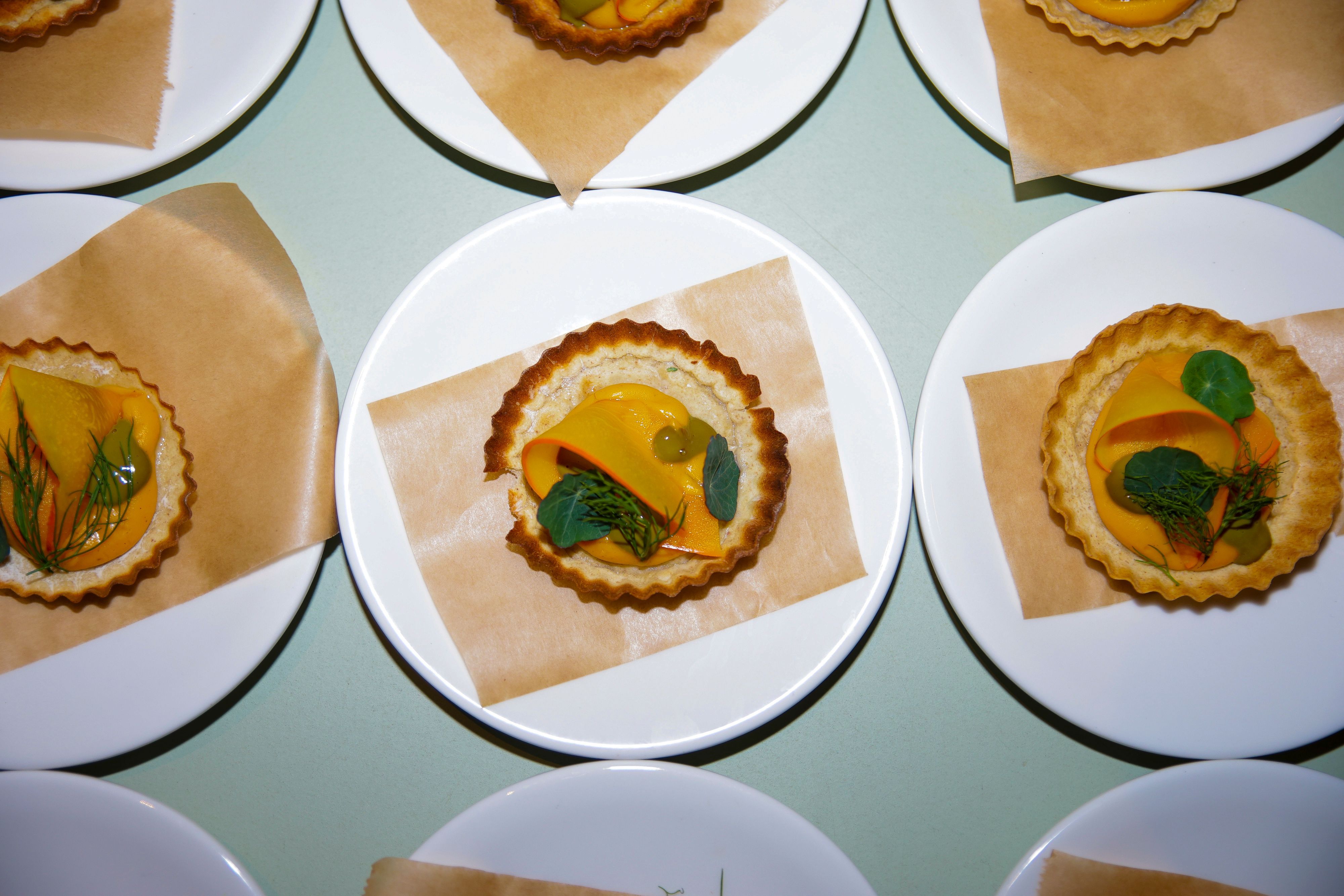 Mehrere Kürbis-Tartelettes liegen auf Tellern.