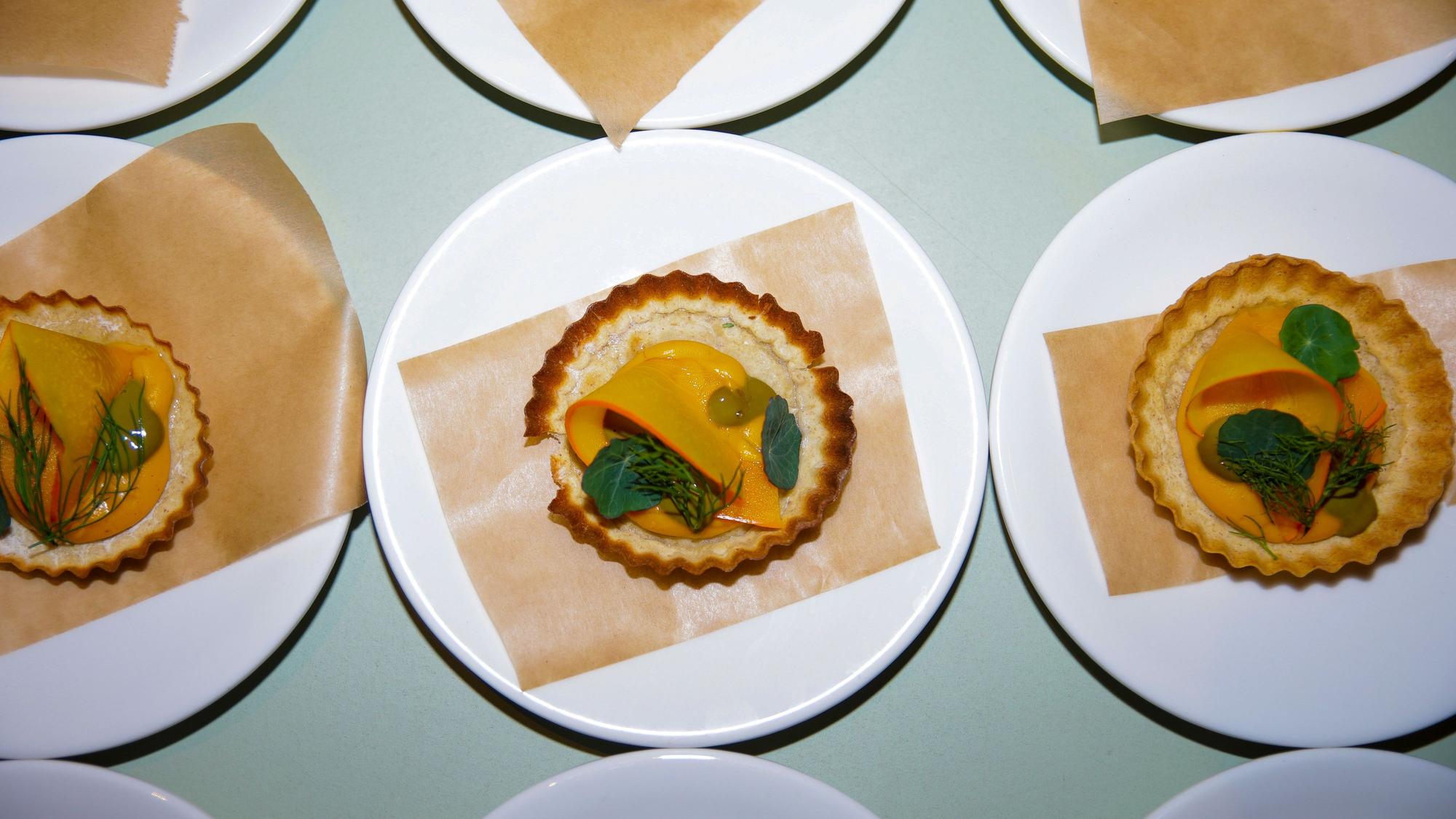 Mehrere Kürbis-Tartelettes liegen auf Tellern.