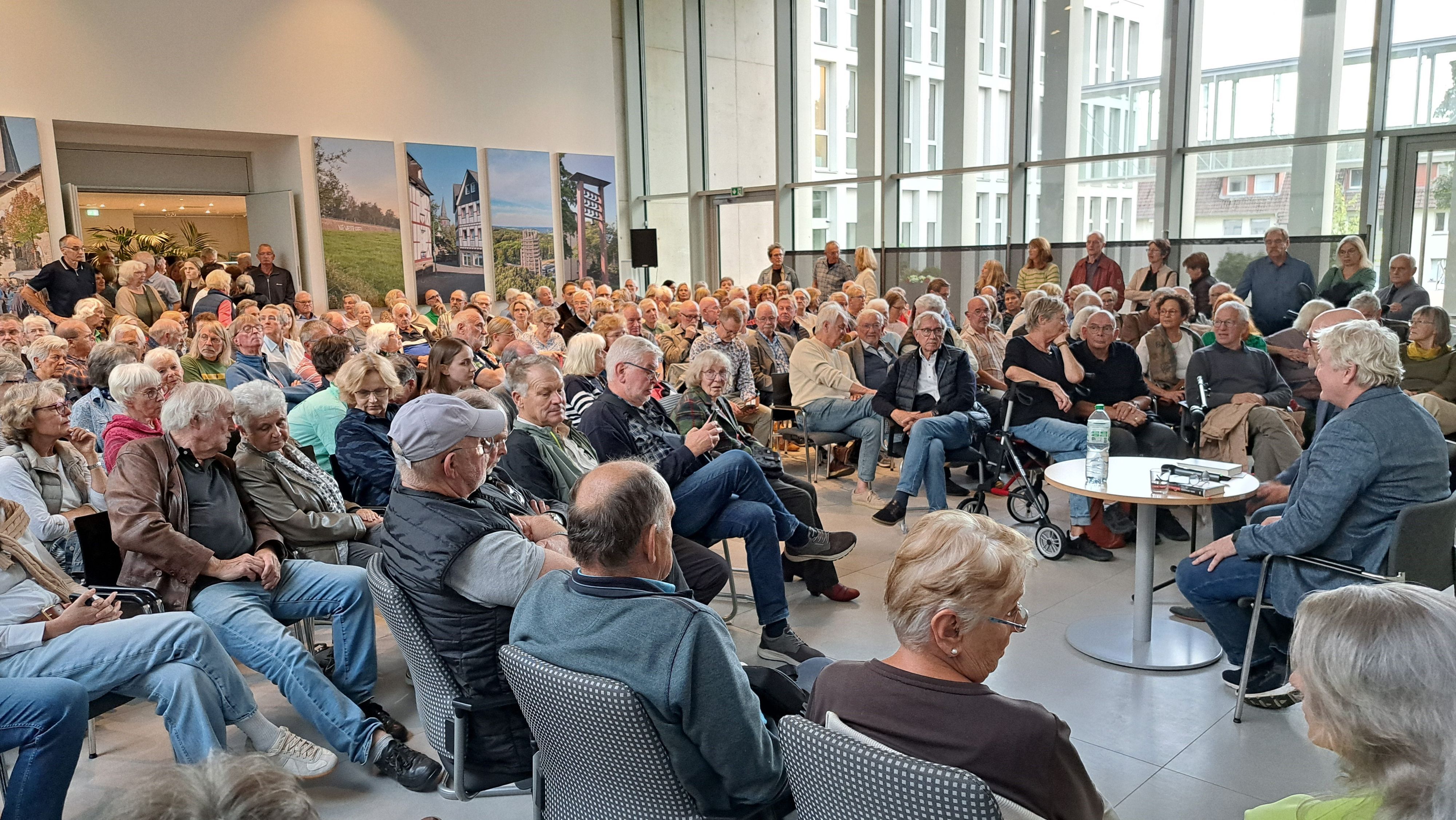 Das Foto zeigt den Buchautor Axel Spilcker und eine große Zahl an Zuhörern.