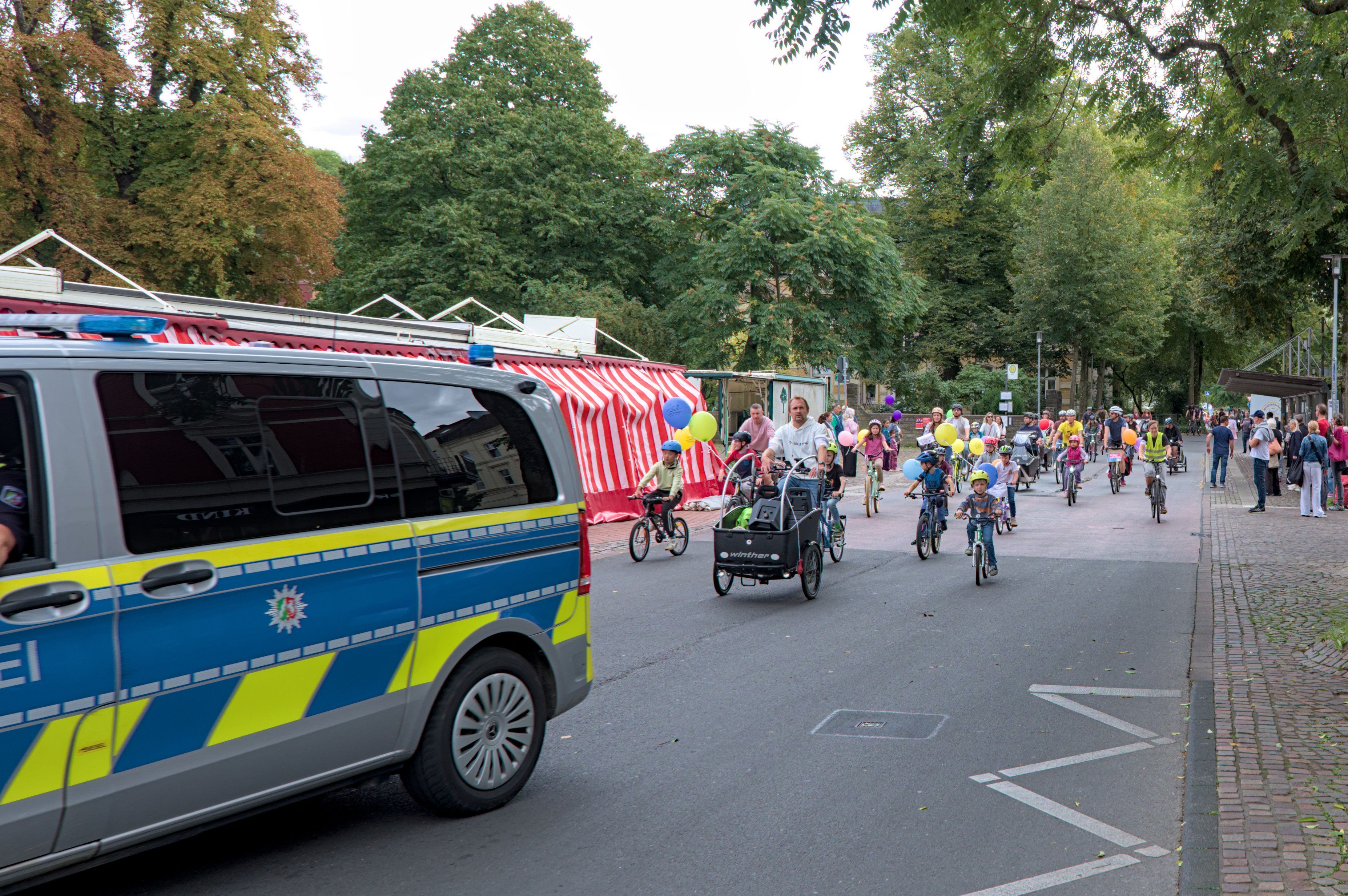 Hinter einem Polizeiwagen fahren Fahrradfahrer.