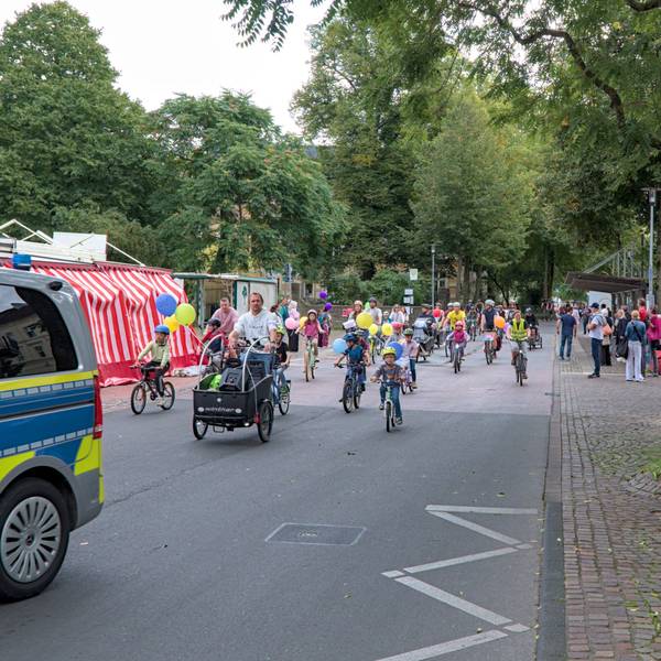 Hinter einem Polizeiwagen fahren Fahrradfahrer.