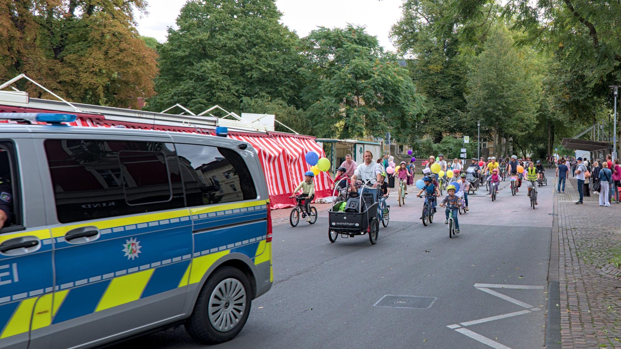 Hinter einem Polizeiwagen fahren Fahrradfahrer.