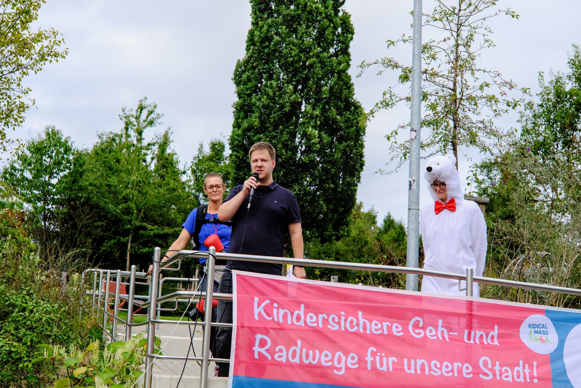 Ein Mann spricht auf einem Wagen in ein Mikrofon.