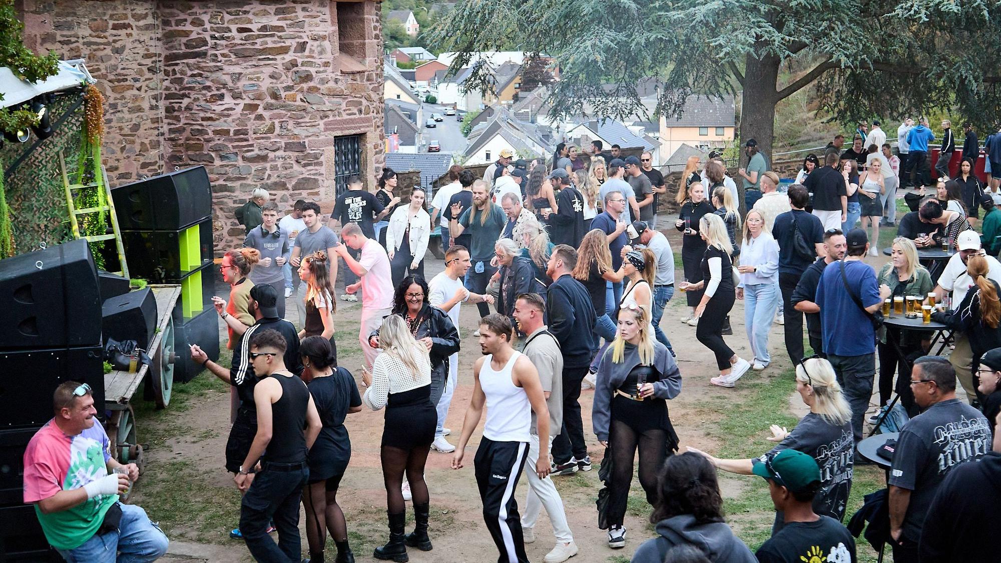Das Bild zeigt zahlreiche Raver im Hof der Burg Hengebach in Heimbach.