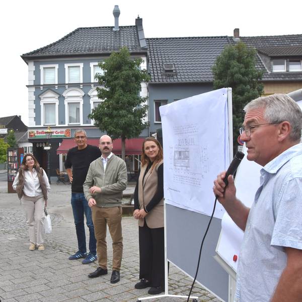 Auf dem Bild ist eine Gruppe von Menschen auf dem Marktplatz zu sehen.