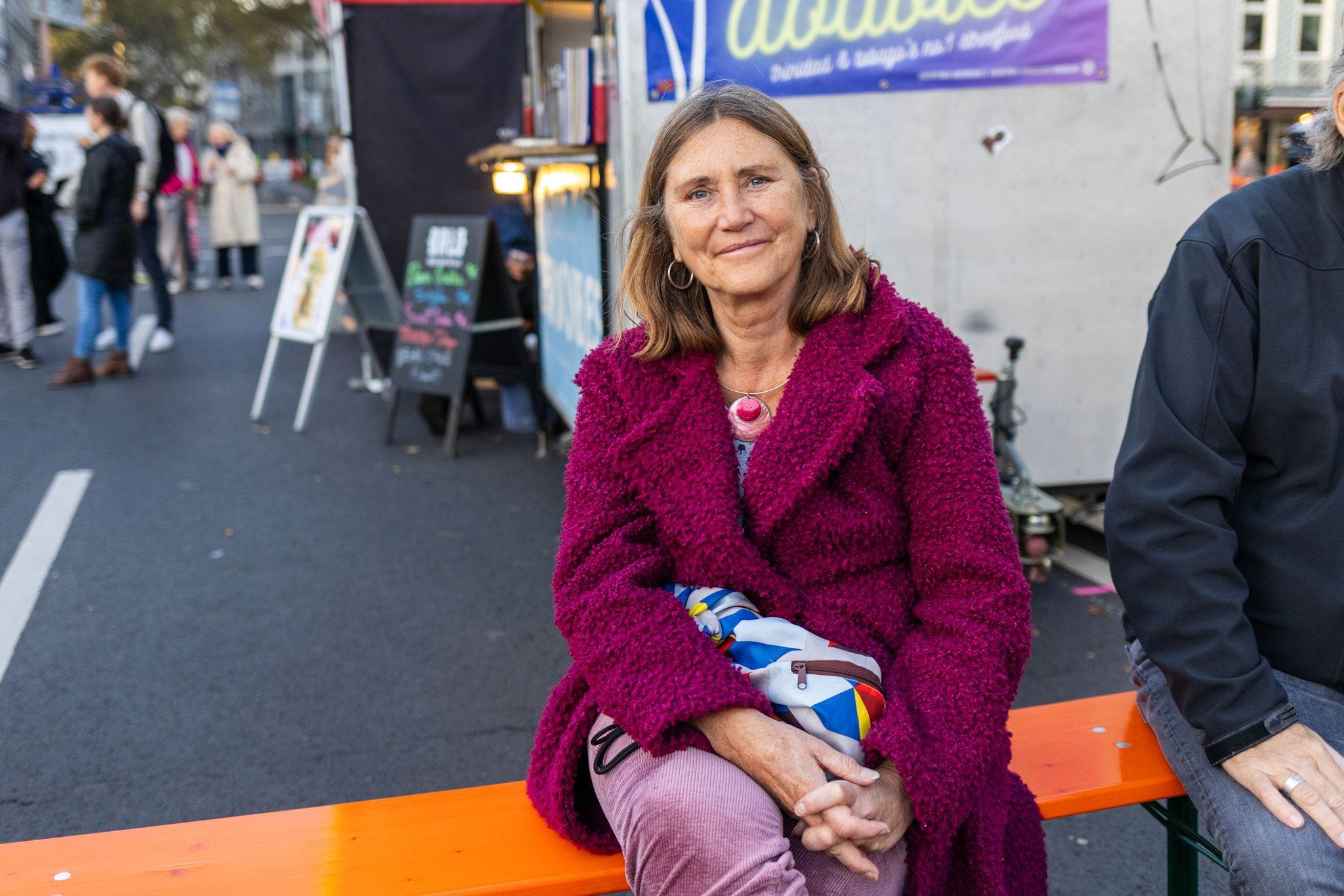 Eine Frau in pinker Jacke lächelt in die Kamera.