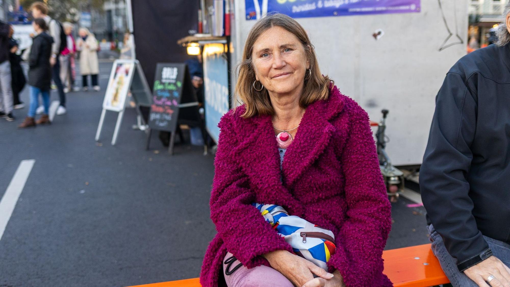 Eine Frau in pinker Jacke lächelt in die Kamera.