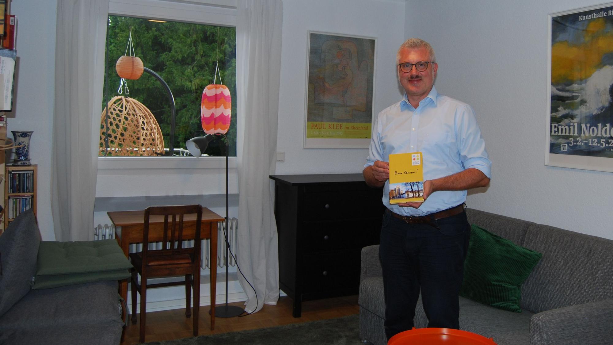 Ein Mann steht vor einem Bettsofa in einem einfach eingerichteten Zimmer