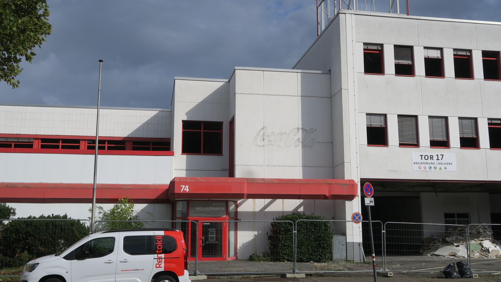 Vor einem dreistöckigen Bürogebäude parkt ein weiß-roter Kleintransporter.