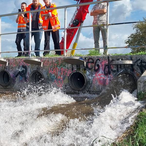 Wasser fließt aus Rohren einen Hang hinunter.