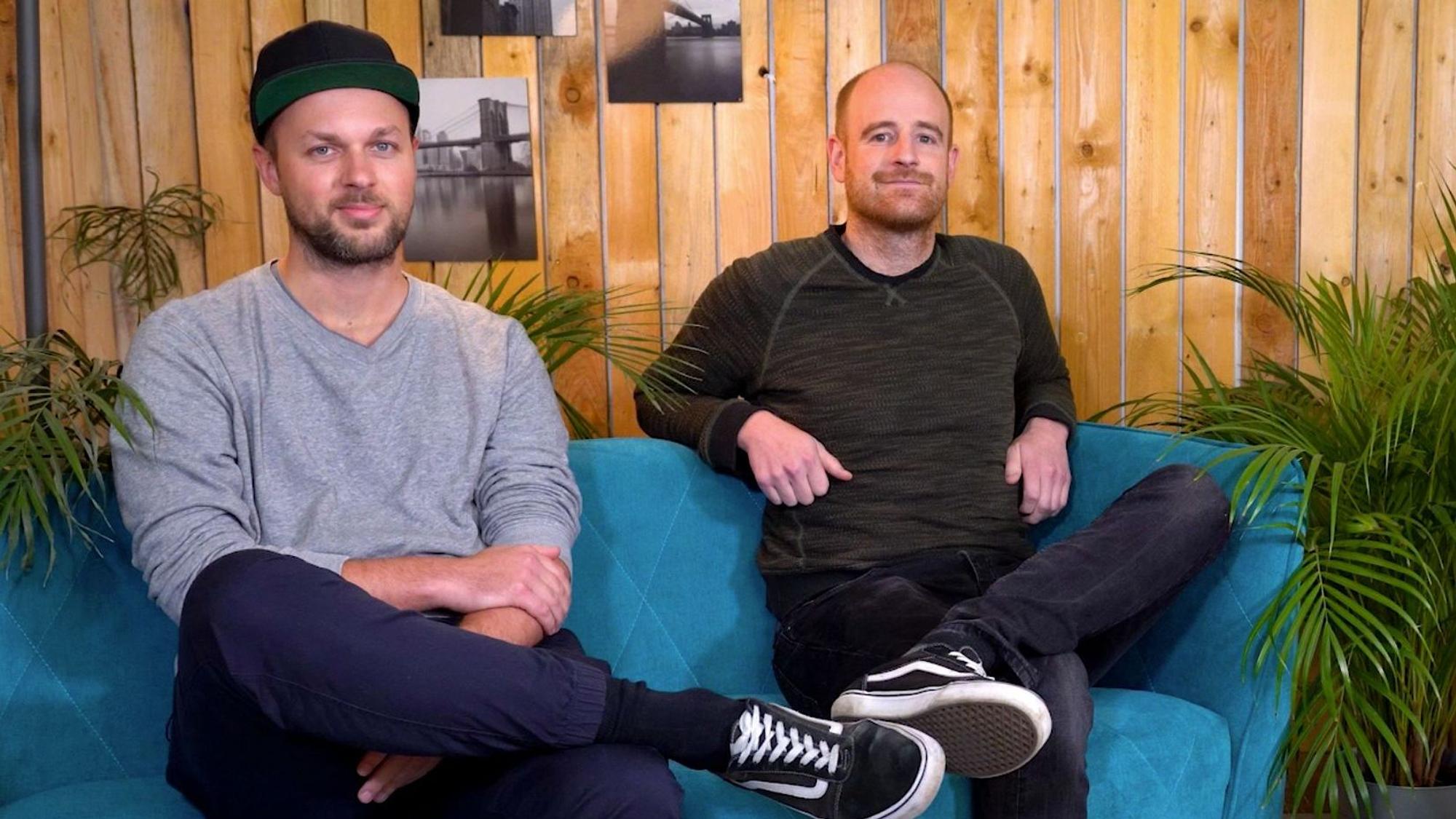 Das Foto zeigt zwei Männer auf einer Couch.