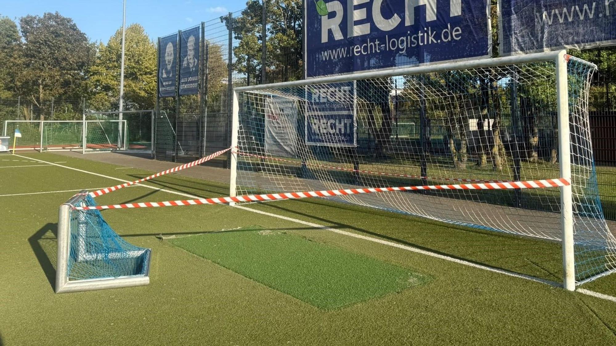 Auf dem Bild ist ein gesperrtes Tor auf einem Kunstrasenplatz zu sehen.