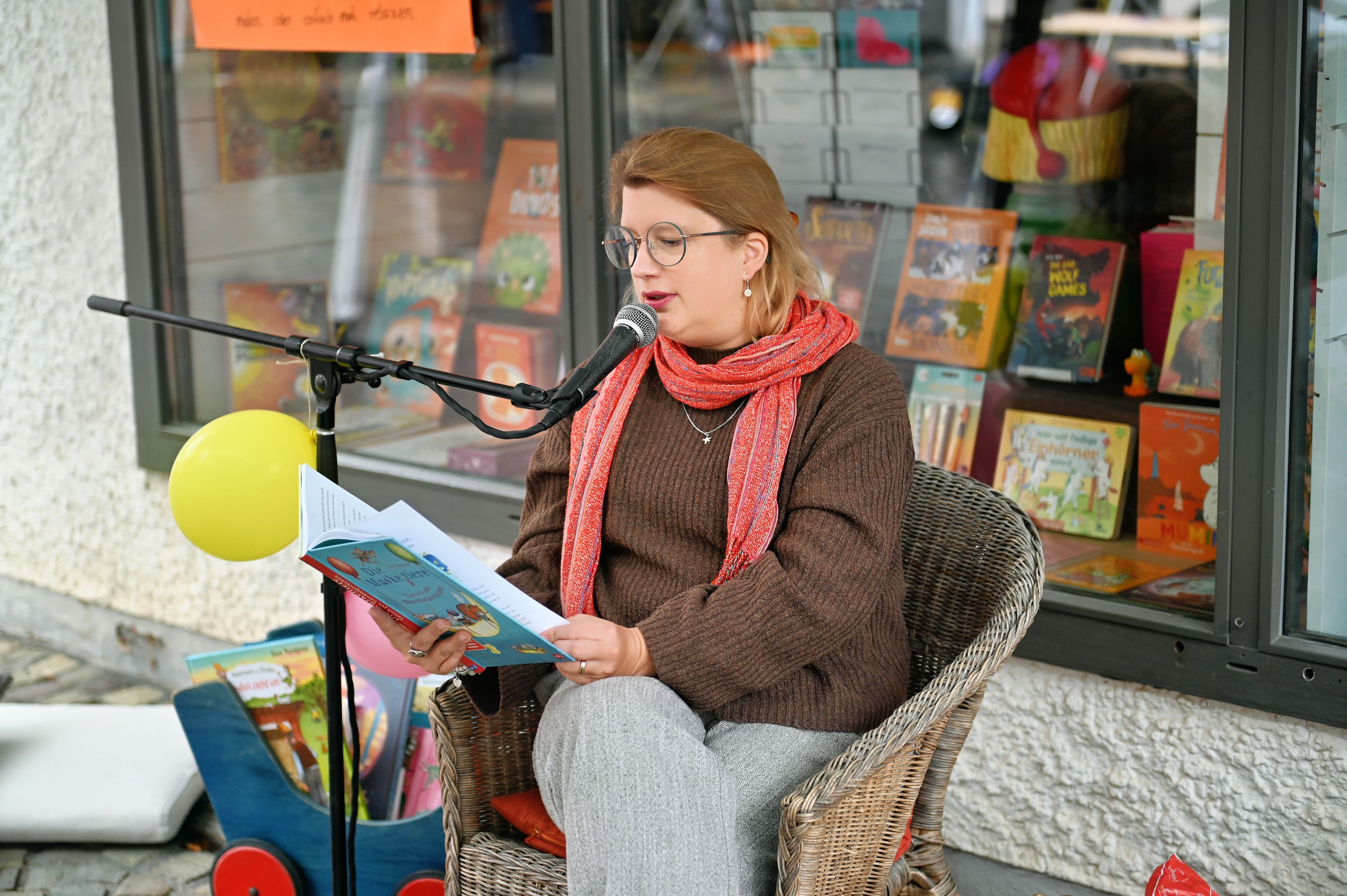 Kathrin Henk sitzt lesend in einem Sessel vor dem Schaufenster der Buchhandlung.