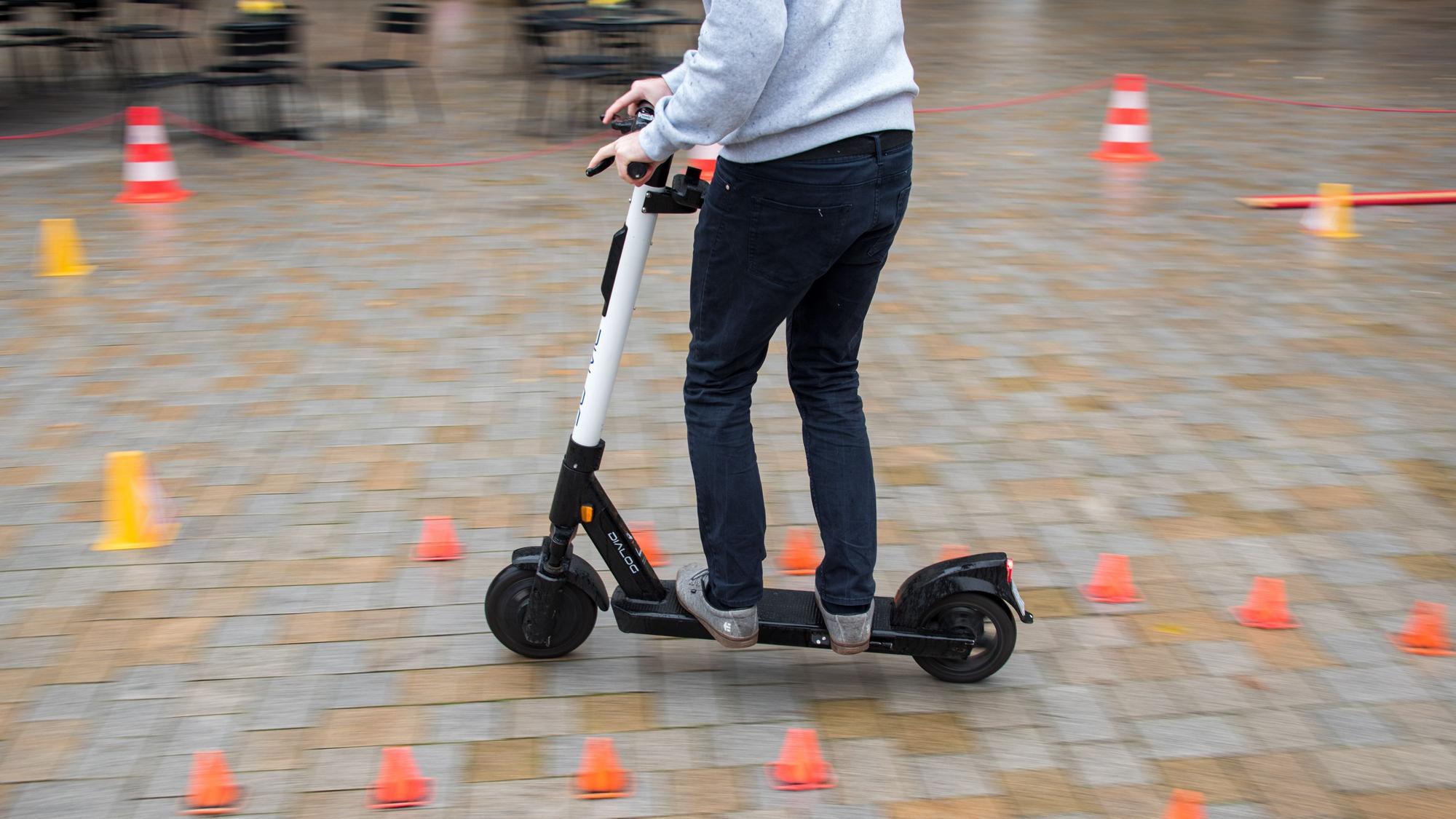 Ein Mitarbeiter eines Anbieters für E-Scooter fährt während eines Fahrsicherheitstrainings durch einen Hindernisparcours.