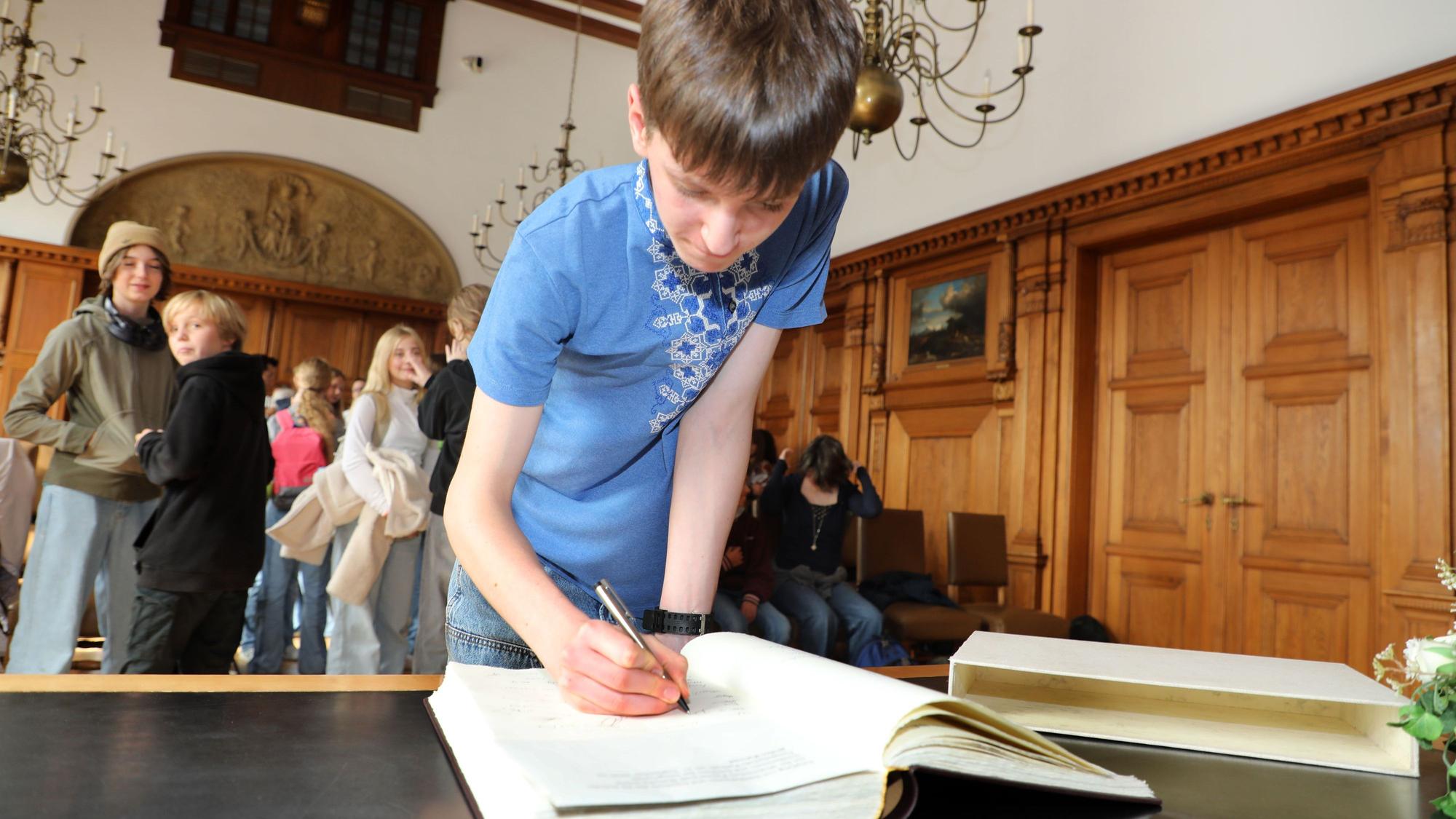 Ins Goldene Buch der Stadt Bergisch Gladbach tragen sich die Jugendlichen aus Butscha ein.