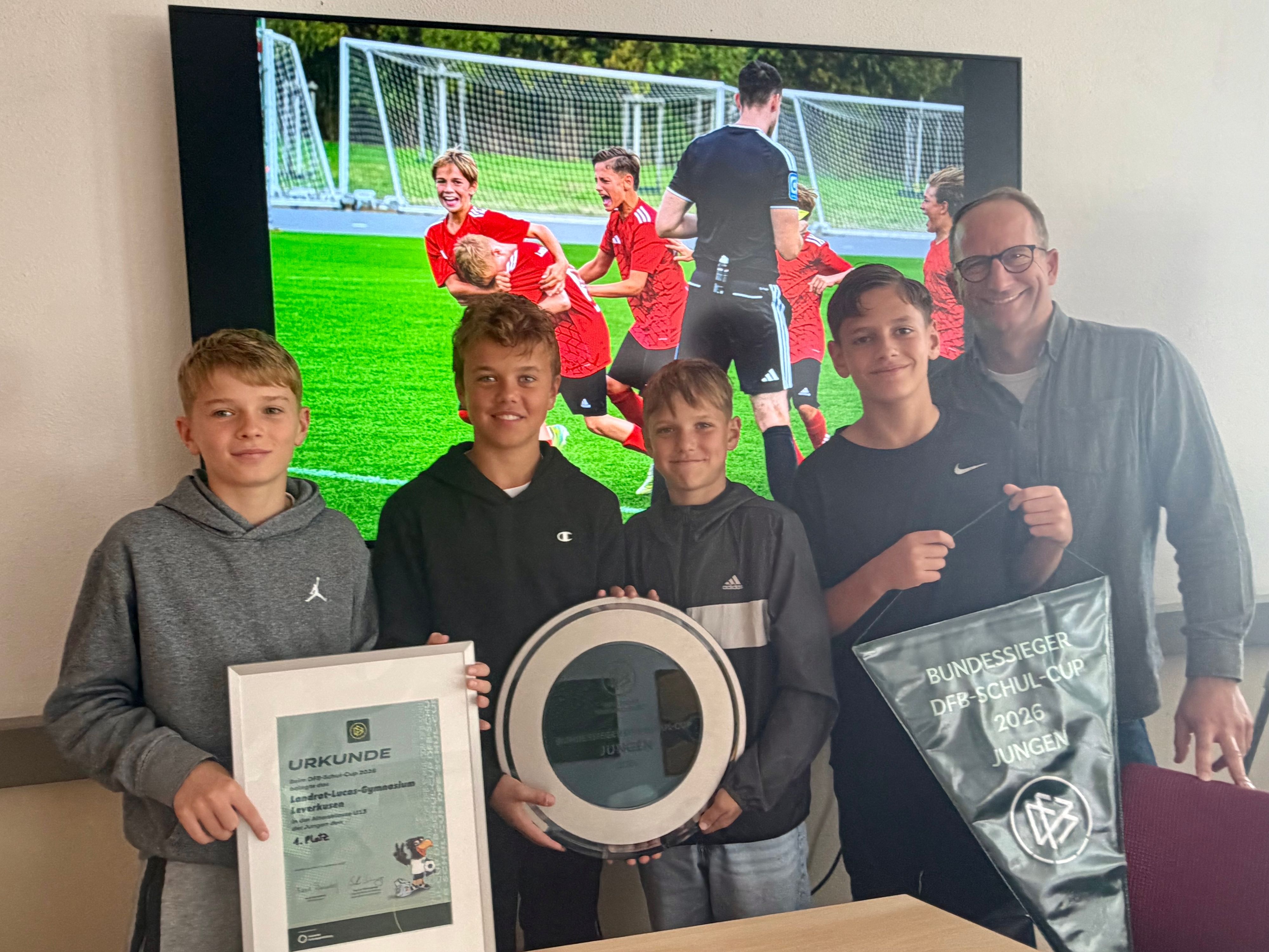 Henrik Kocerba, Rune Kilberth, Taylan Kaz, Konstantin Nuss und Lehrer Benedikt Ditscheid mit den Trophäen im Landrat-Lucas-Gymnasium.