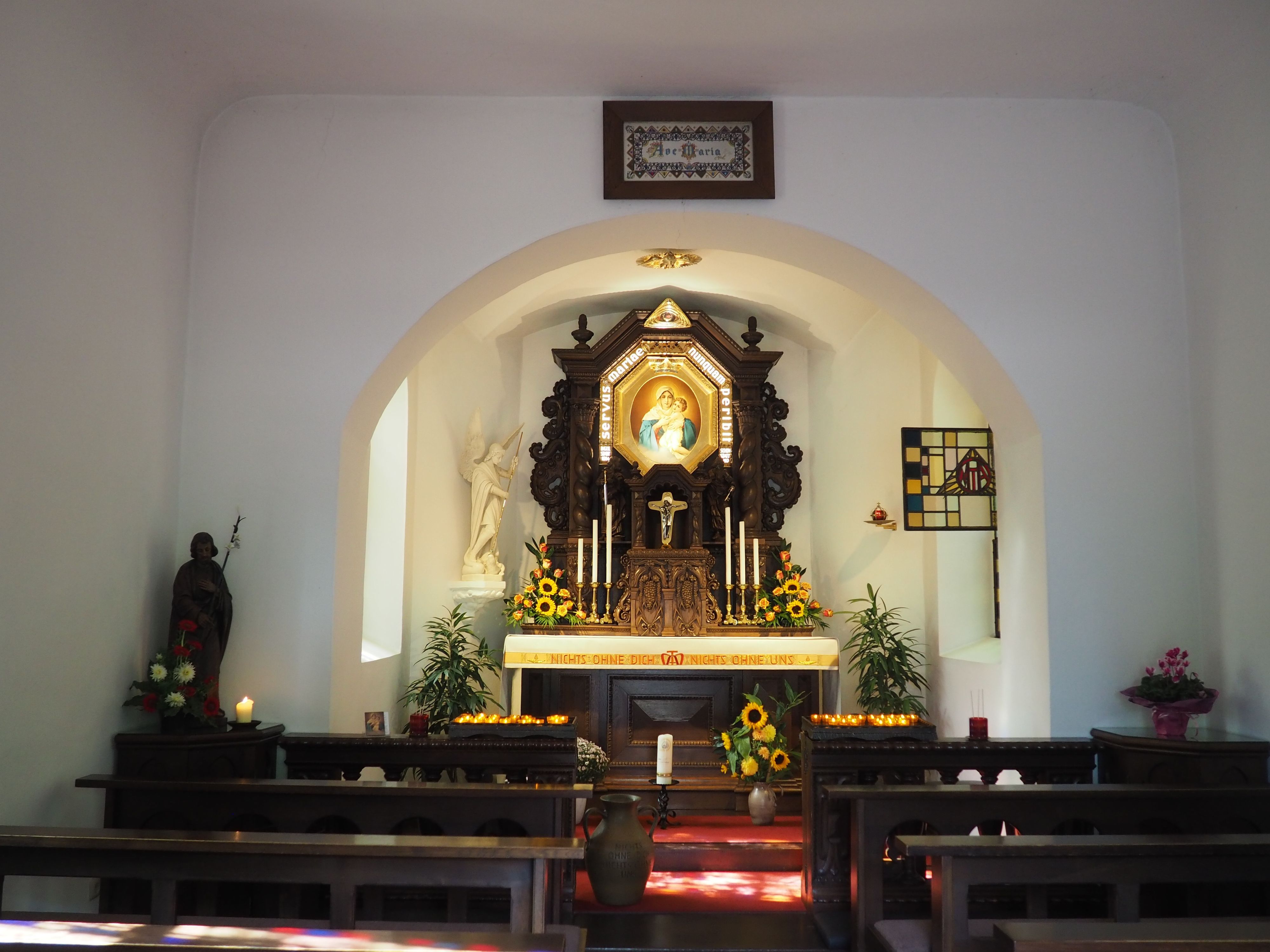 Vor dem Altar in der Kapelle brennen Kerzen.