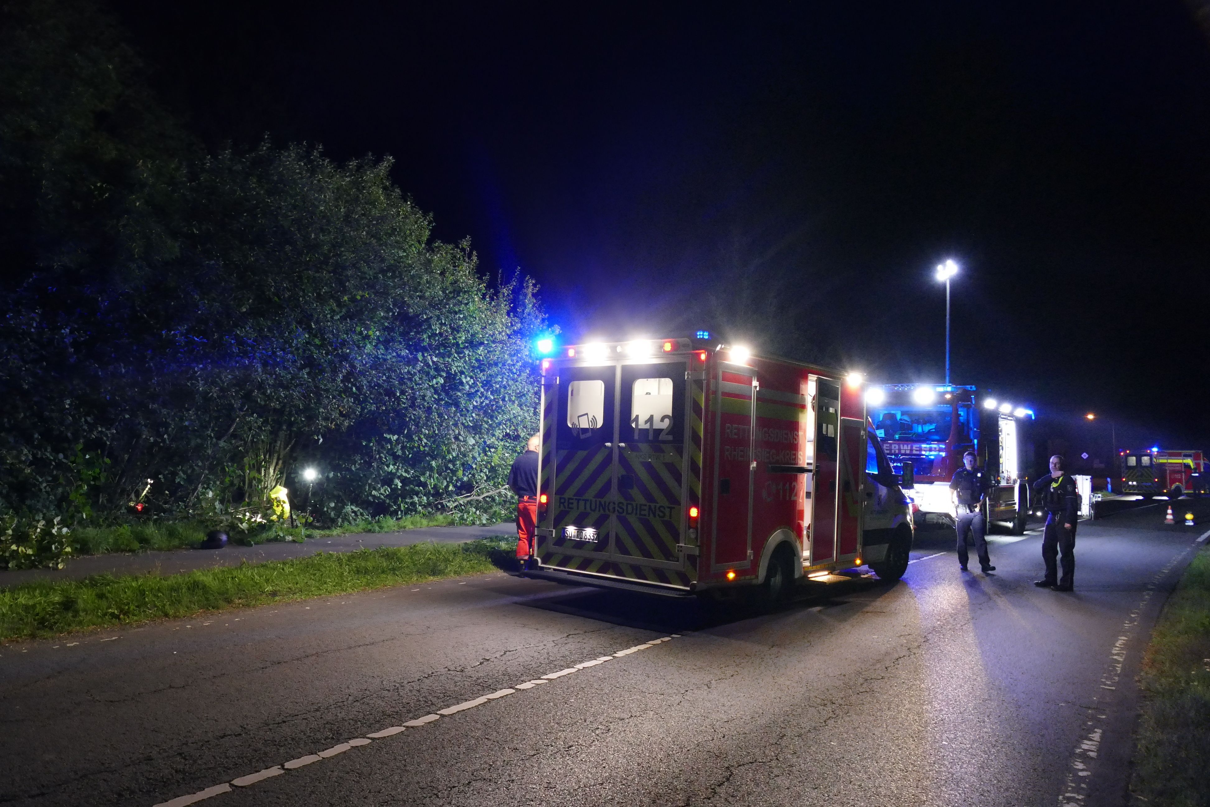 Einsatzkräfte von Feuerwehr und Rettungsdienst nachts an einer Unfallstelle.