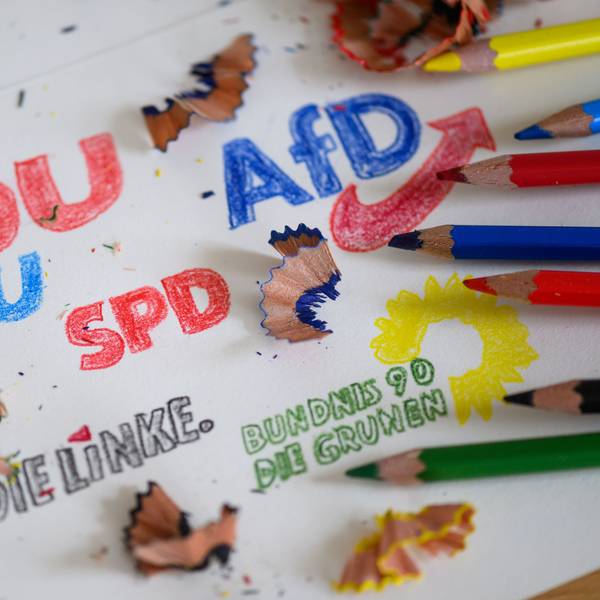Die Logos der Parteien CDU/CSU, SPD, Die Linke, Bündnis 90/Die Grünen und AfD sind mit Buntstiften auf ein Blatt gezeichnet.