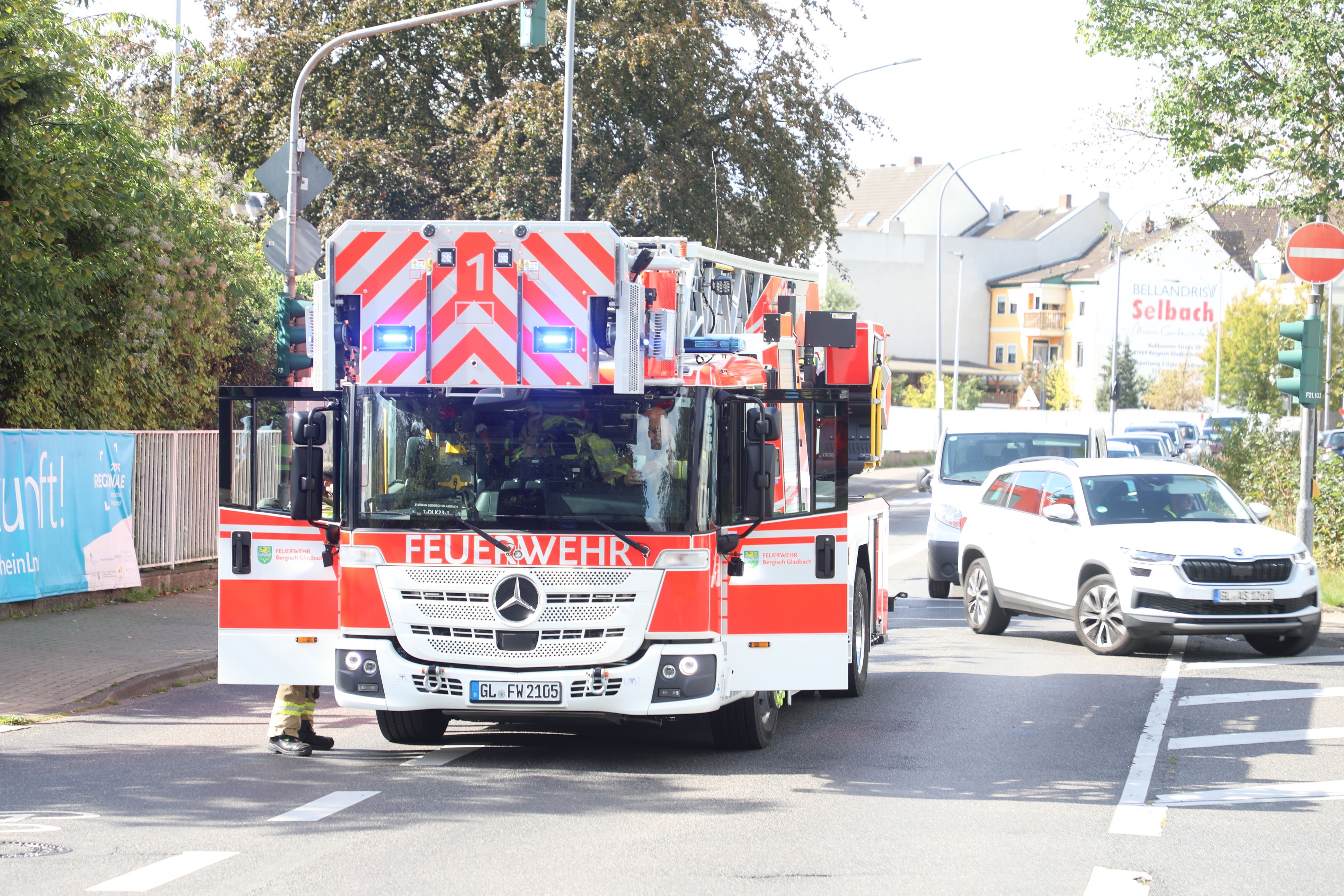 Eine Drehleiter der Feuerwehr steht auf der Straße, Autos wenden davor.