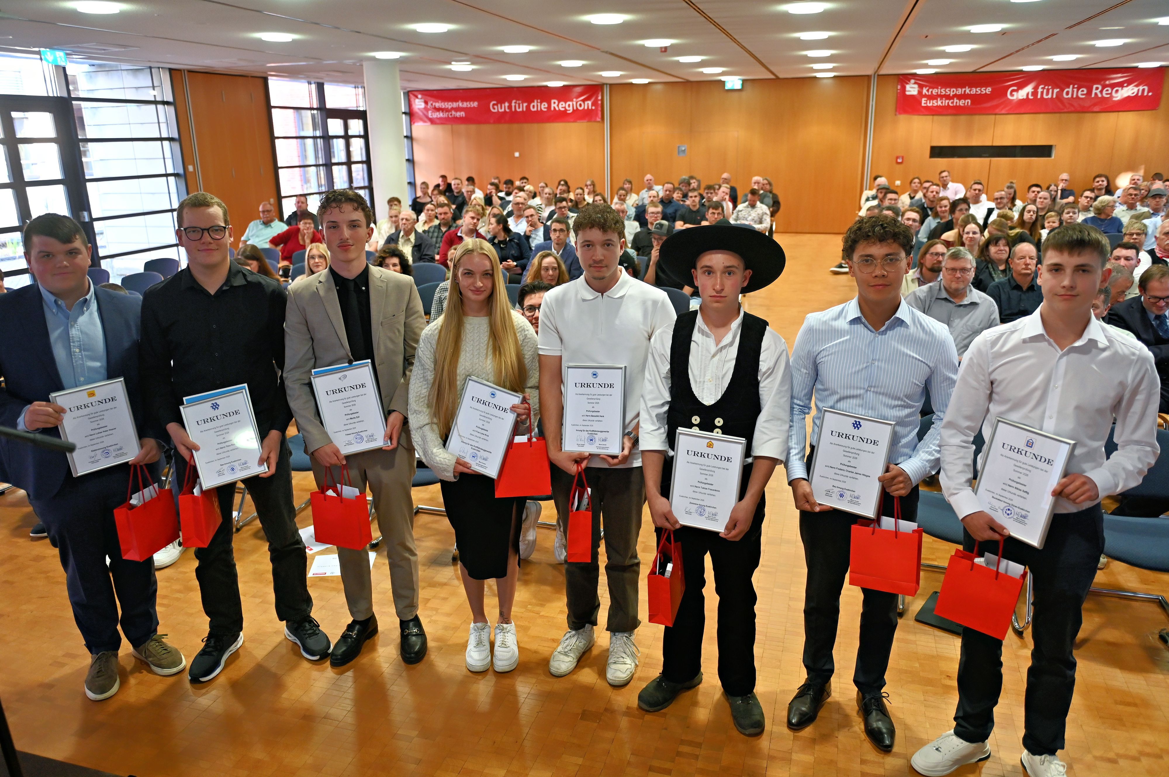Sieben junge Männer und eine junge Frau stehen nebeneinander. Sie sind als die Besten der Gesellenprüfungen ausgezeichnet worden.