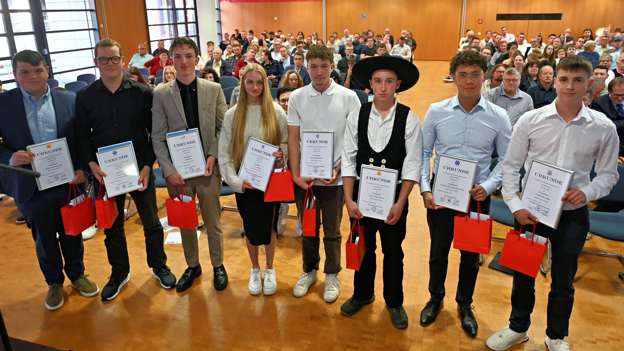 Sieben junge Männer und eine junge Frau stehen nebeneinander. Sie sind als die Besten der Gesellenprüfungen ausgezeichnet worden.