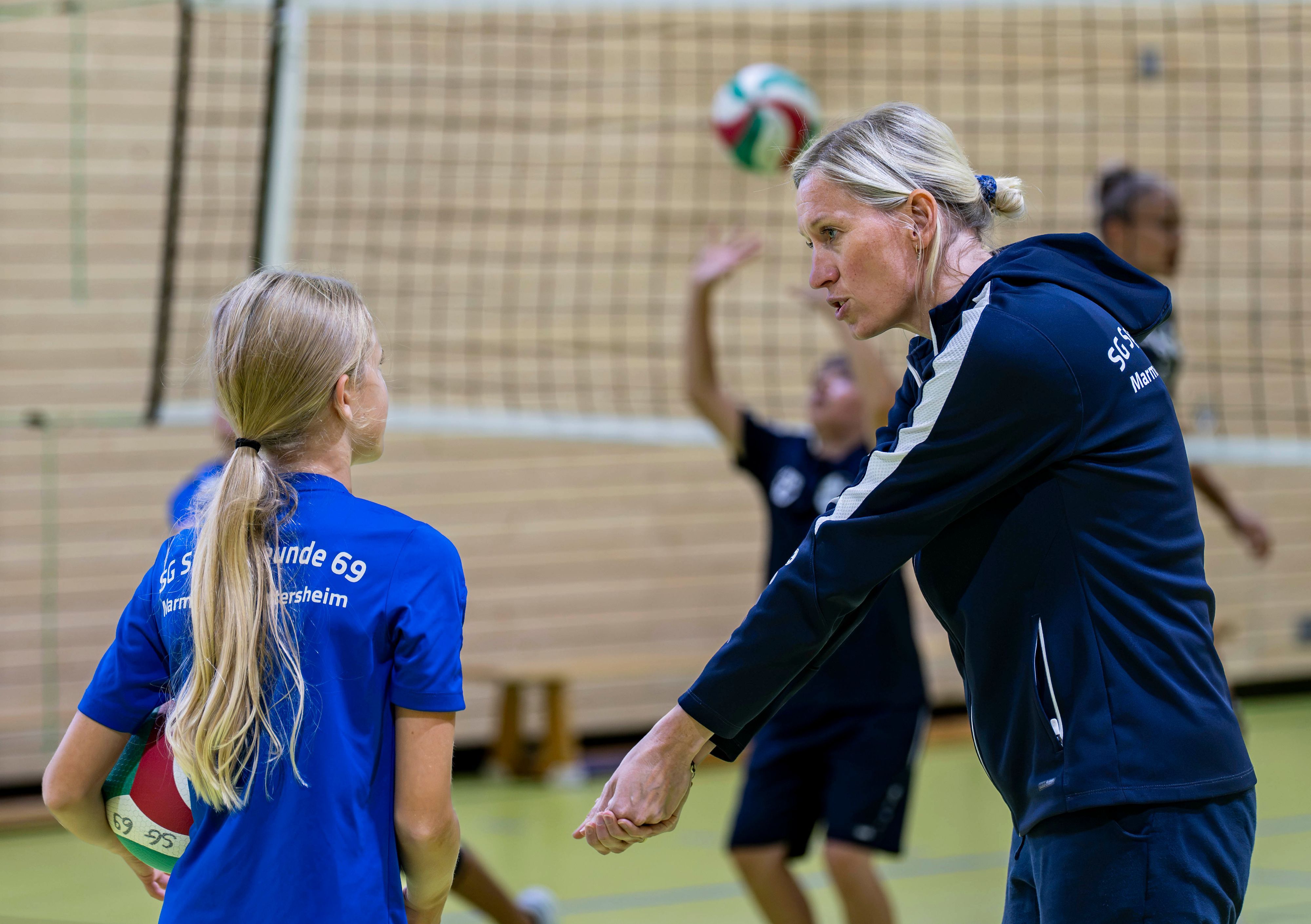Trainerin Judith Pelzer erklärt einer Nachwuchsspielerin, wie sie einen Ball annimmt.