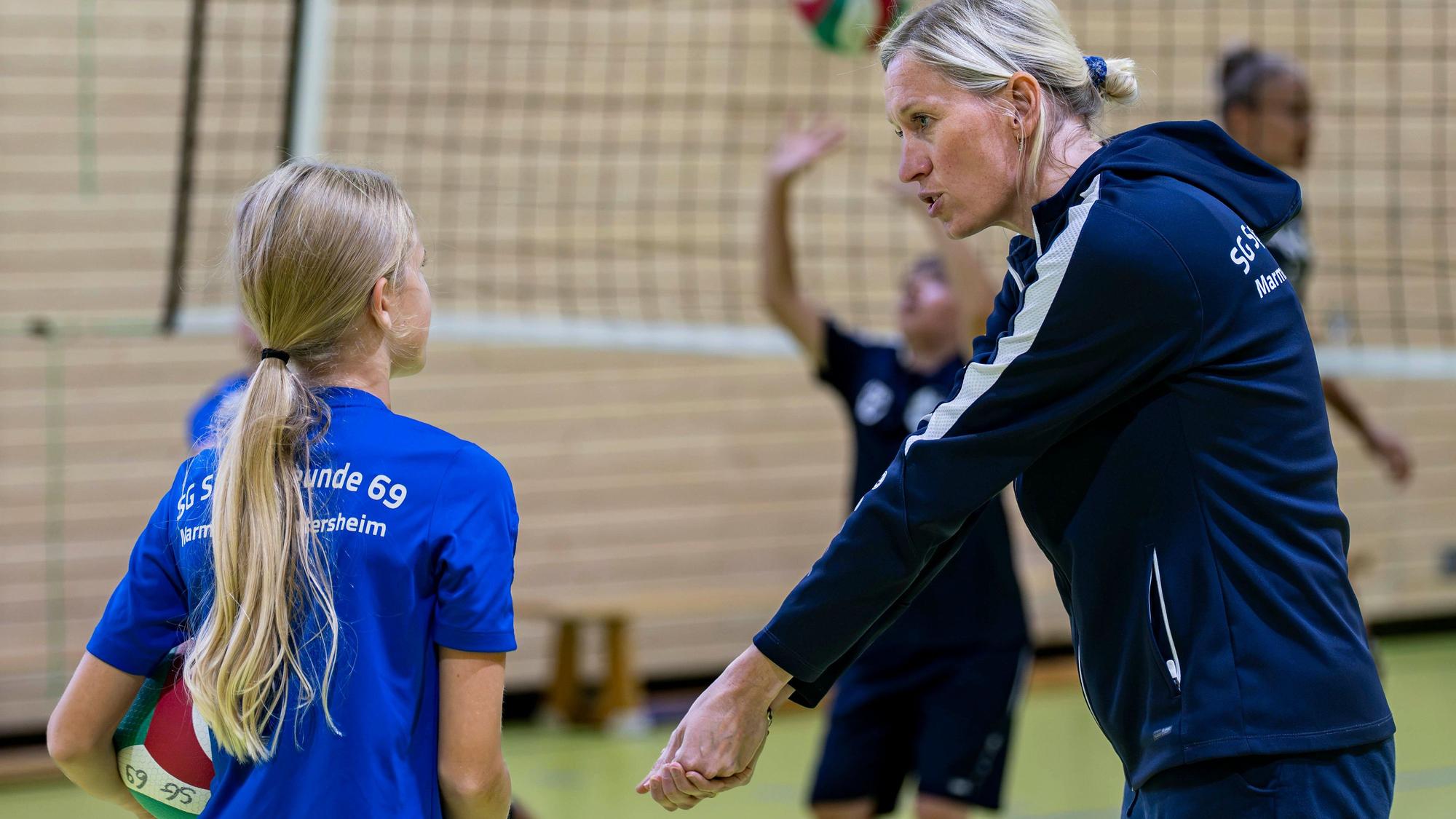 Trainerin Judith Pelzer erklärt einer Nachwuchsspielerin, wie sie einen Ball annimmt.