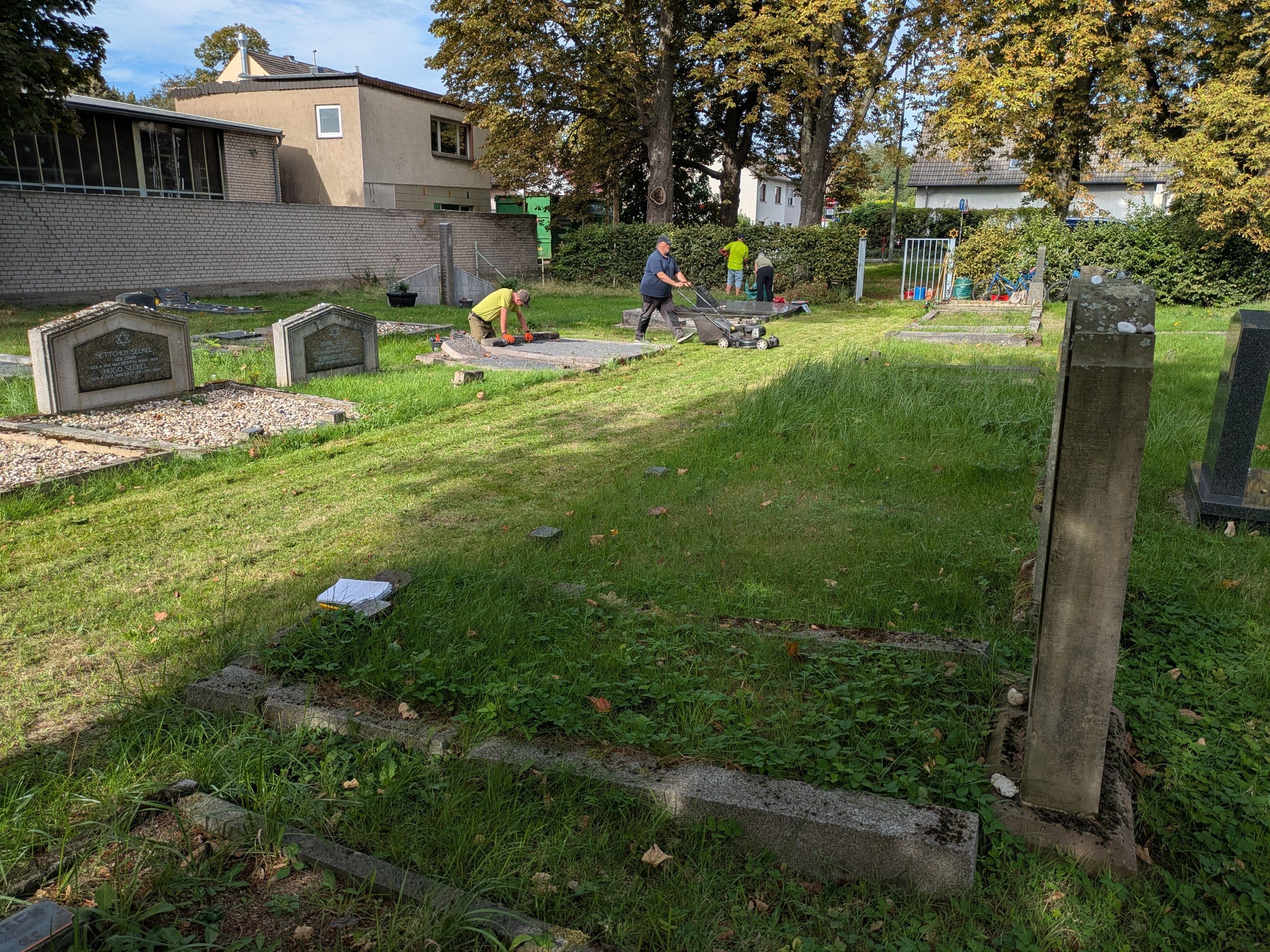 Menschen arbeiten auf einem jüdischen Friedhof.