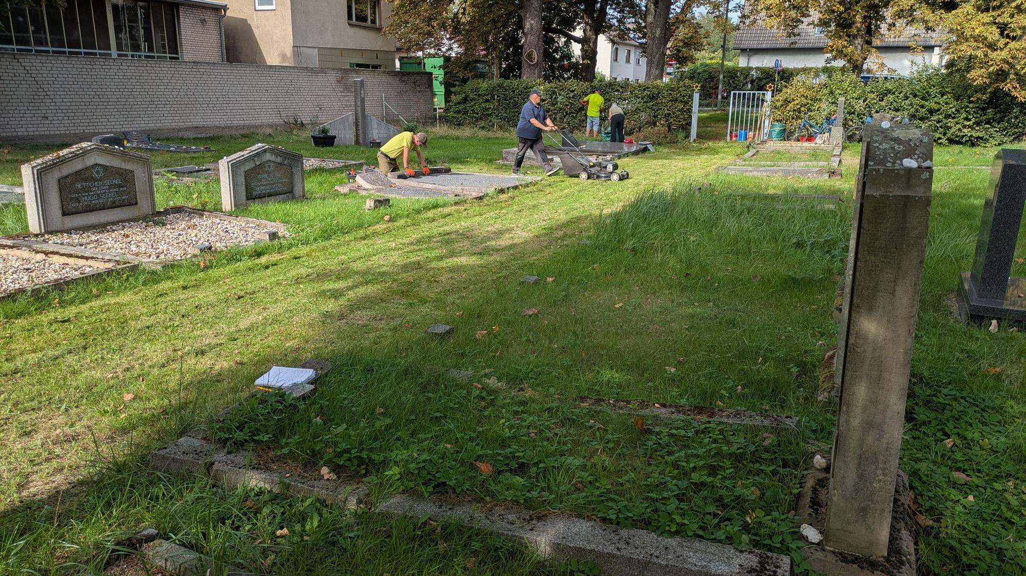 Menschen arbeiten auf einem jüdischen Friedhof.