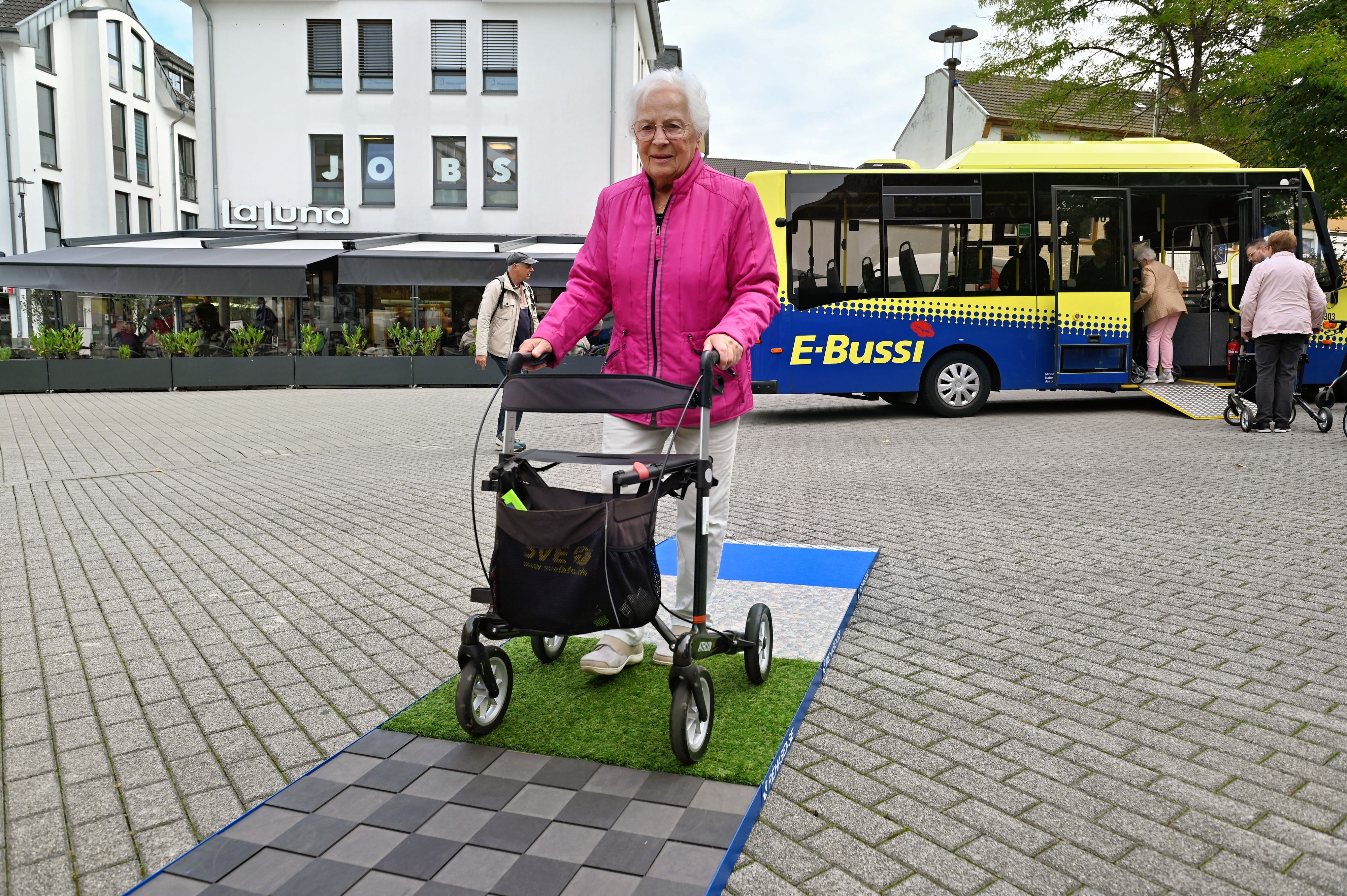Eine Frau schiebt einen Rollator über verschiedene Beläge.